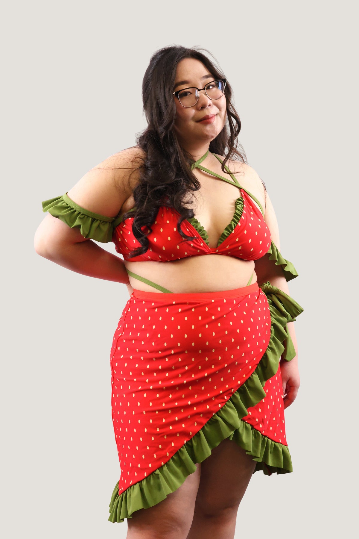 Model wearing a red and green outfit with ruffled details on a plain background