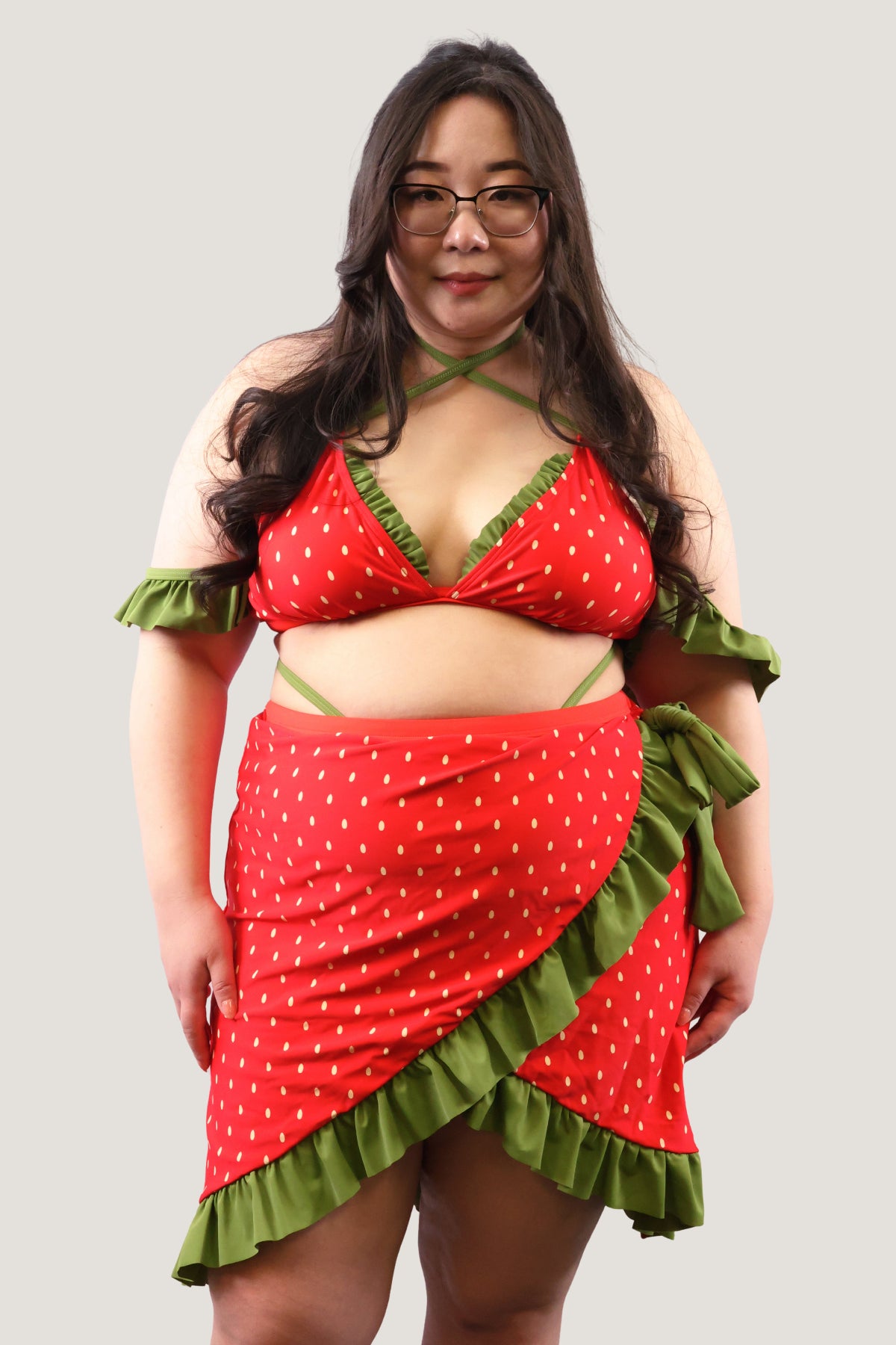 Model wearing a red and green strawberry-themed outfit on a plain background