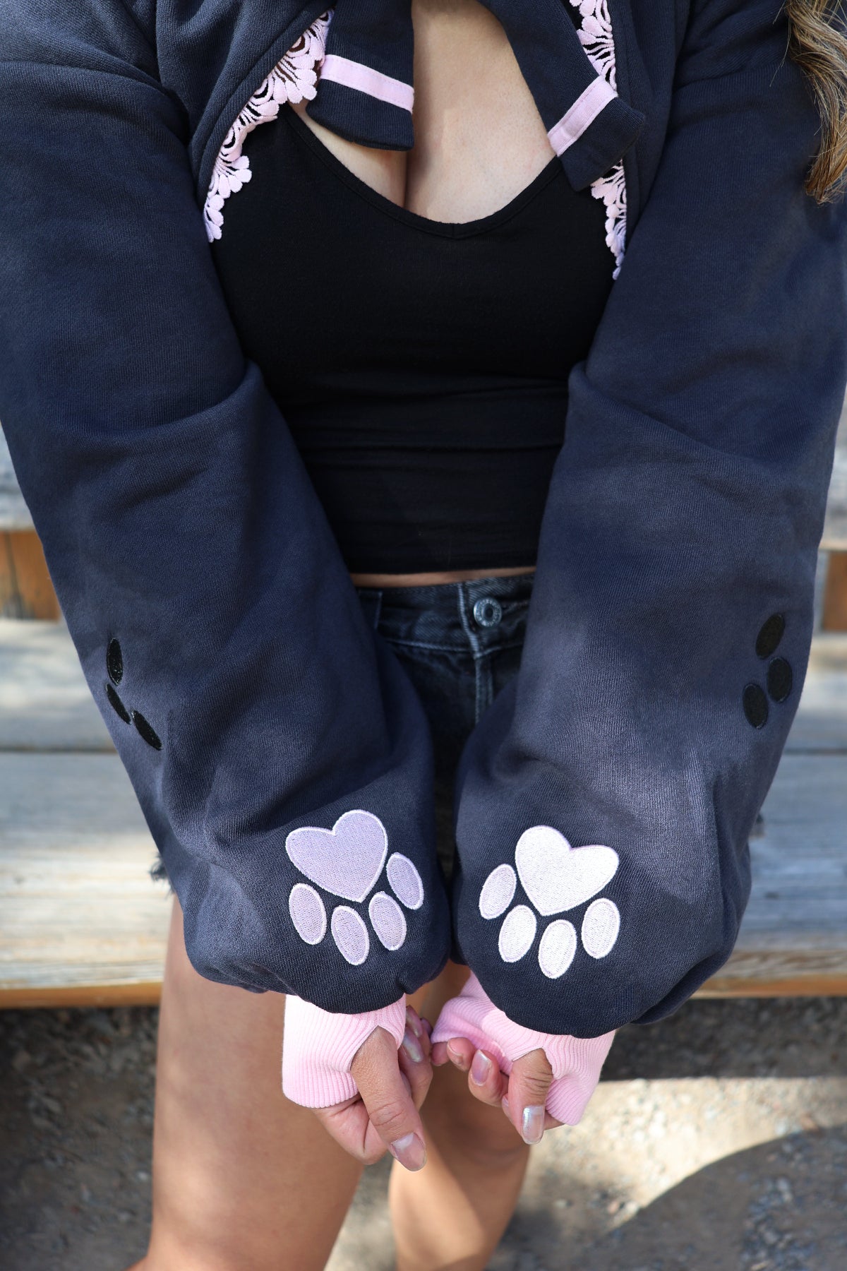 Detail view of the Nyahallo Cat Shrug featuring oversized sleeves, embroidered heart-shaped paw print cuffs, and pink ribbed thumbhole cuffs.