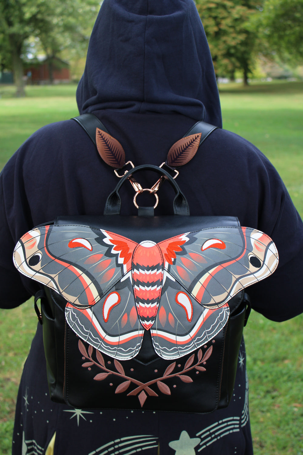 Black backpack featuring a large cecropia moth wing design worn outdoors, inspired by entomology fashion and woodland fairycore aesthetics.