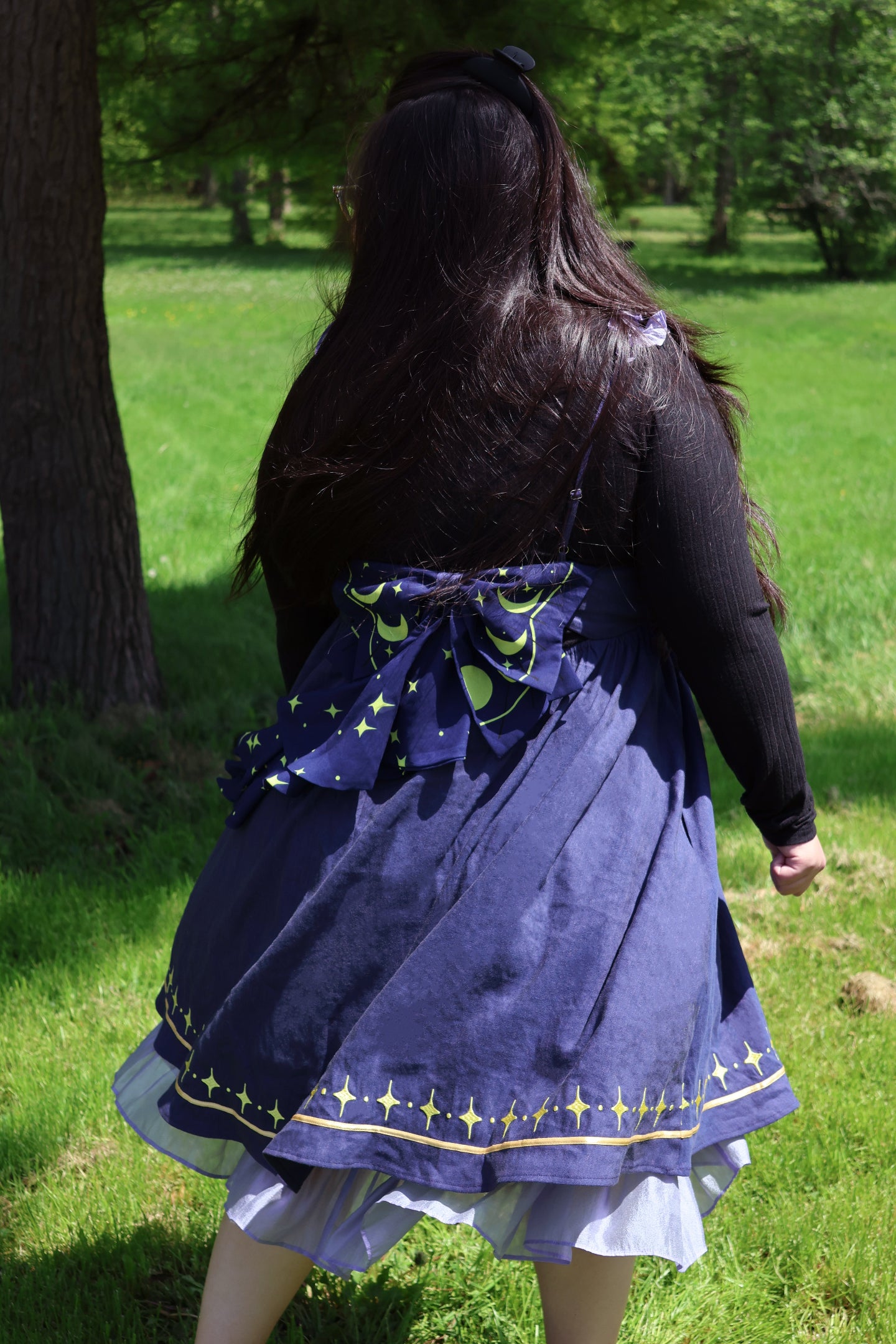 Back view of a cosmic moth dress featuring a celestial bow, starry hem details, and whimsical fairycore fashion styling outdoors