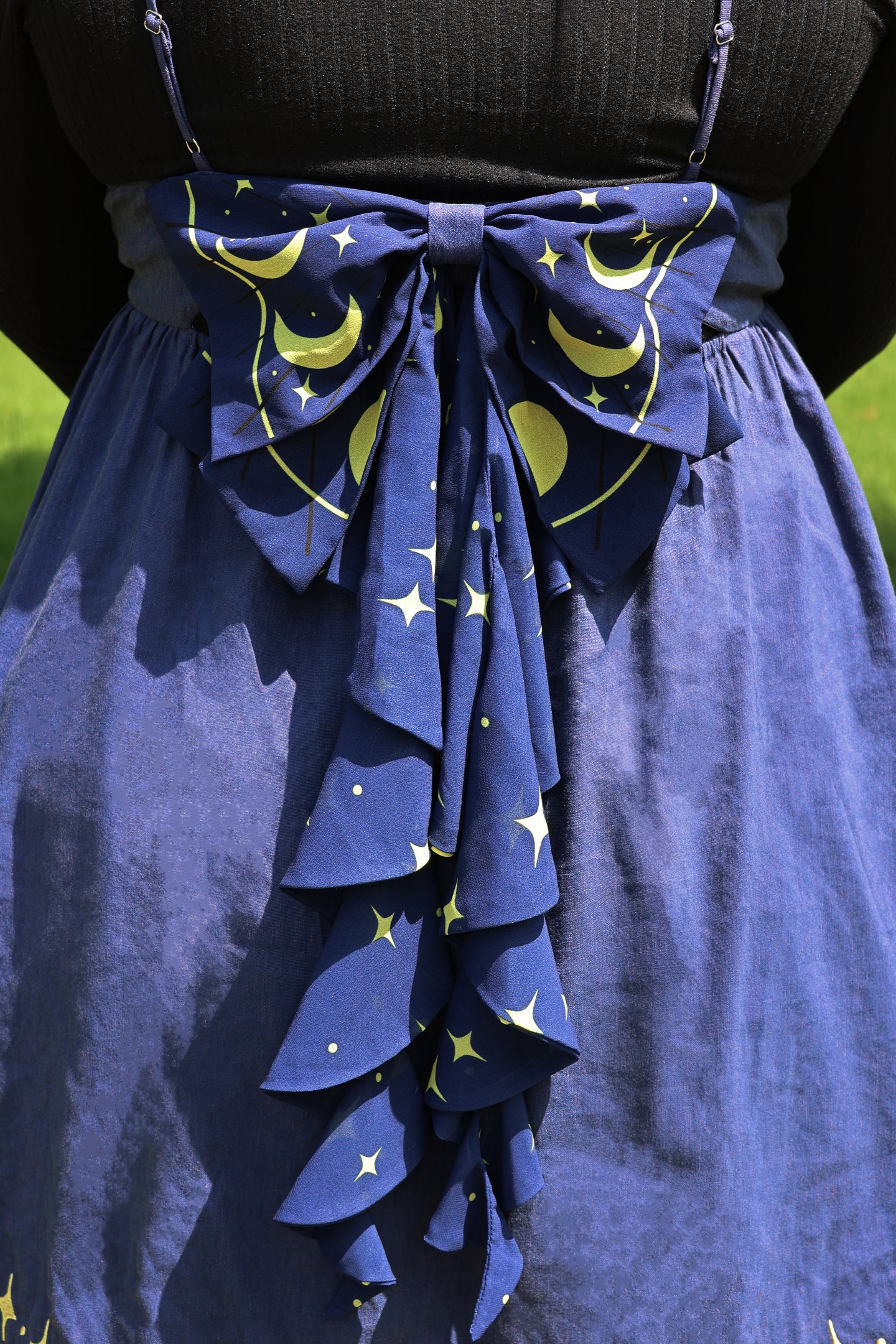 Close-up of the Cosmic Moth Dress featuring an oversized moon and star print bow with cascading celestial tails