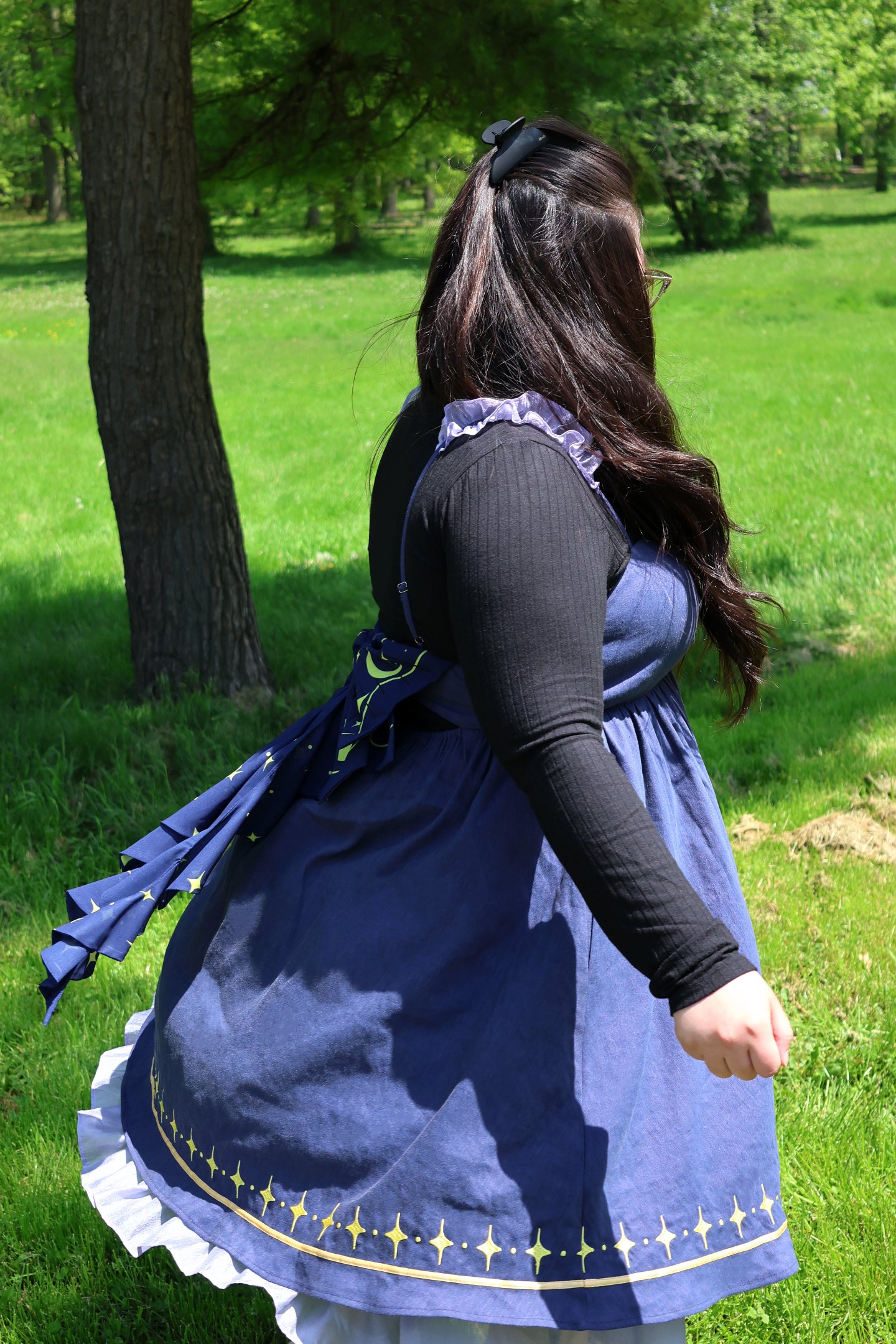 Side view of a cosmic moth dress featuring a celestial bow, star-pattern hem, and flowing fairycore silhouette outdoors