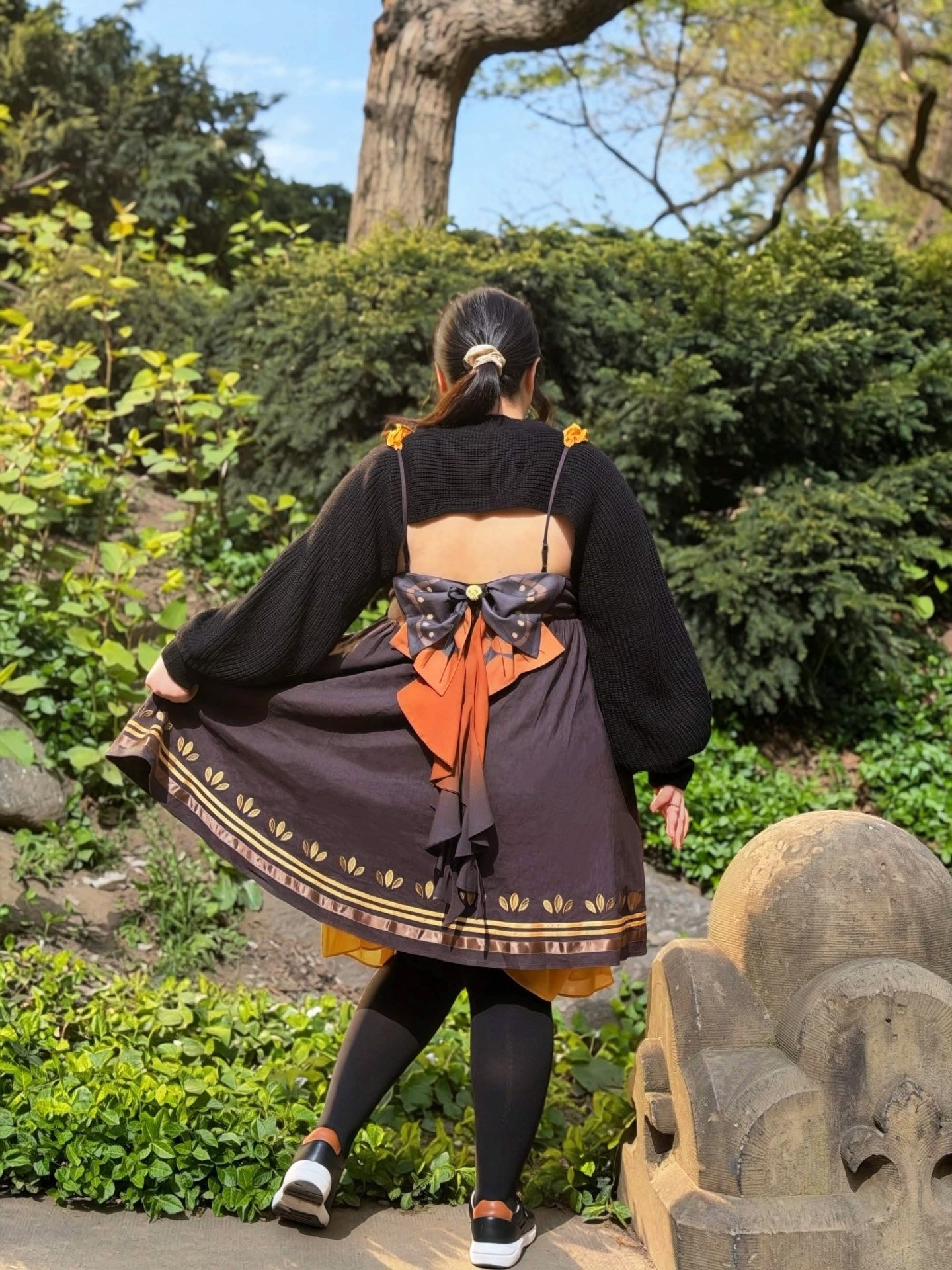 Back view of the Death’s-Head Hawkmoth Dress featuring layered moth wing bows, flowing ribbon details, and an open-back design in a garden setting.