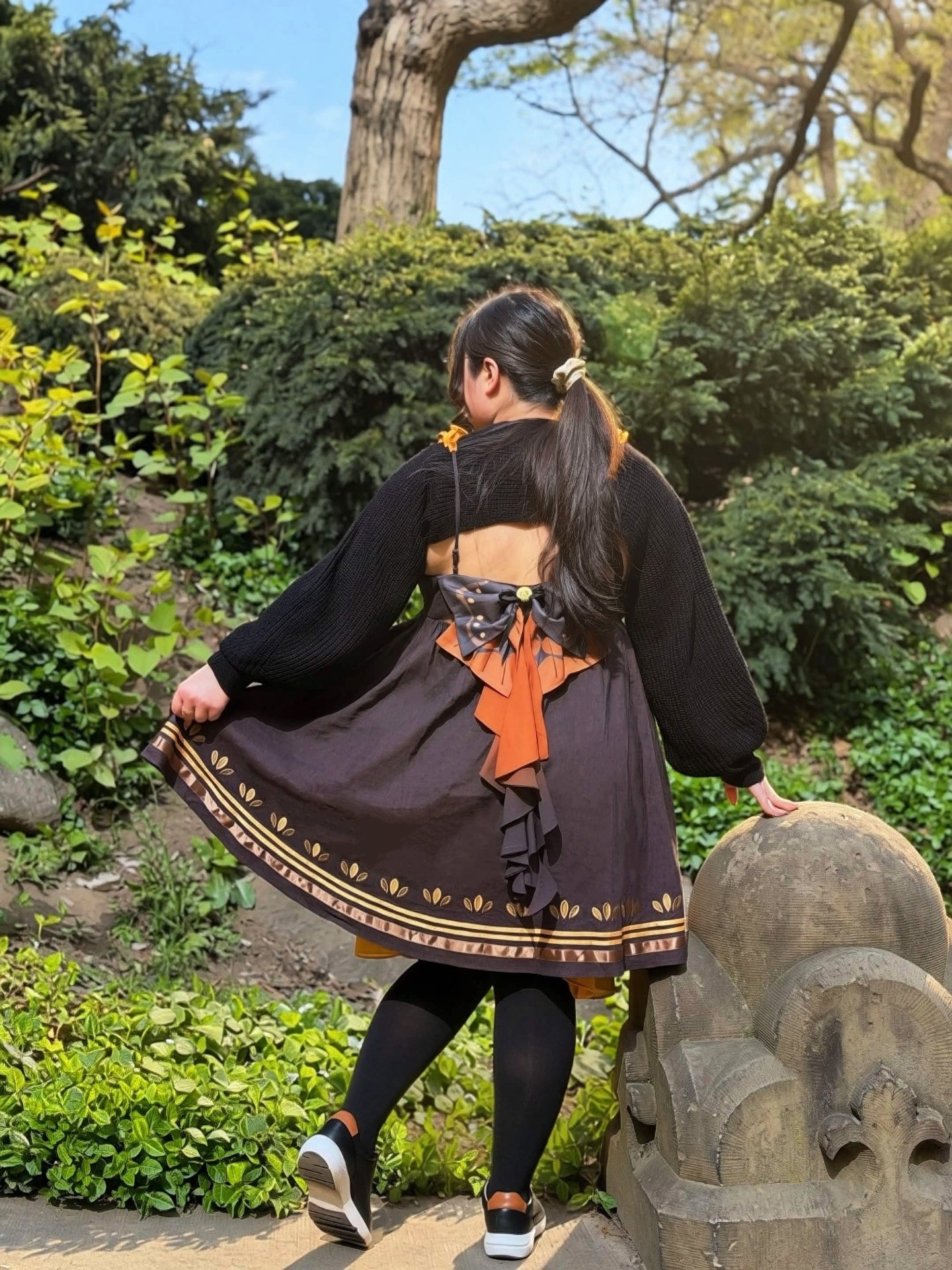 Side back view of the Death’s-Head Hawkmoth Dress featuring moth-inspired bows, flowing layered ribbons, and an open-back silhouette in a sunlit garden.