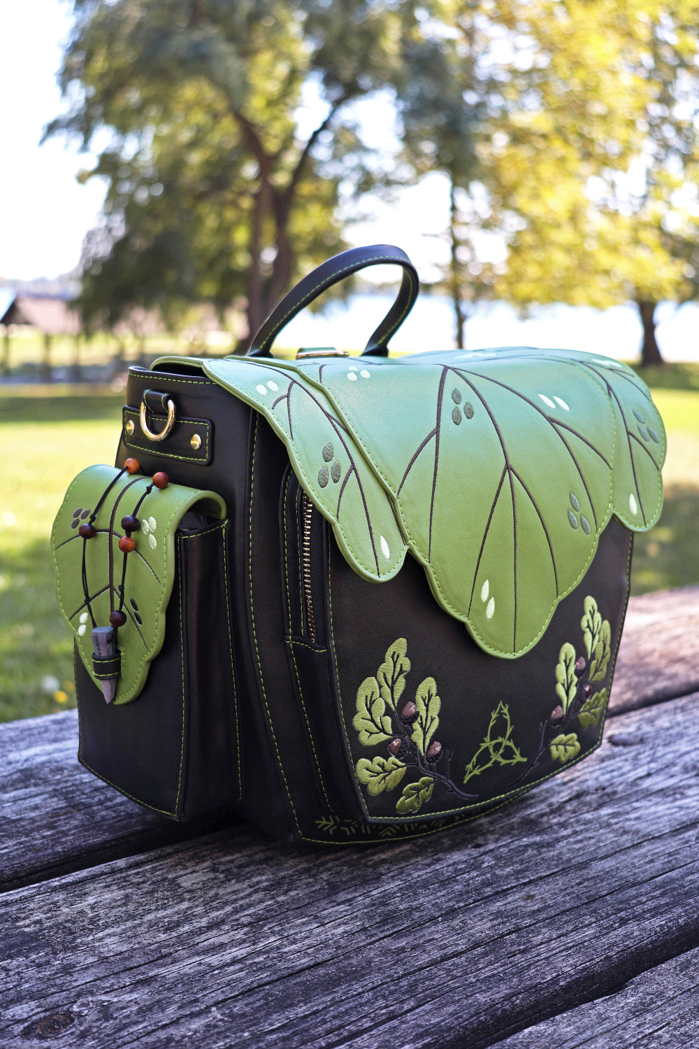 Green and dark brown leaf themed bag on a wooden surface with a blurred natural background