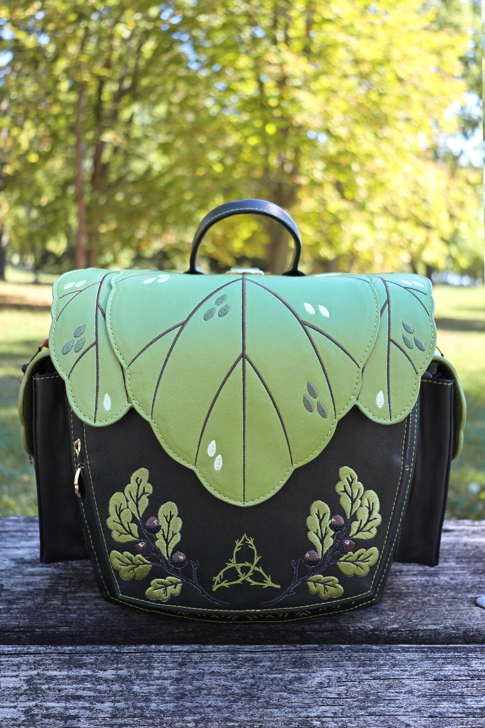 Handbag with leaf design on a wooden surface outdoors