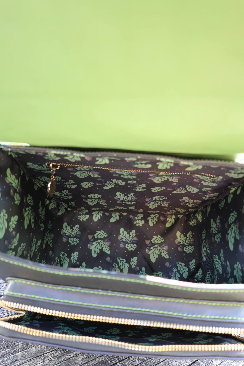 The interior design of the bag features a repeating oak leaf and acorn pattern on a dark background. The leaves are stylized but clearly oak-shaped with lobed edges, paired with small acorns throughout. The print gives a woodland, nature-inspired feel that matches the druid/forest theme of the bag