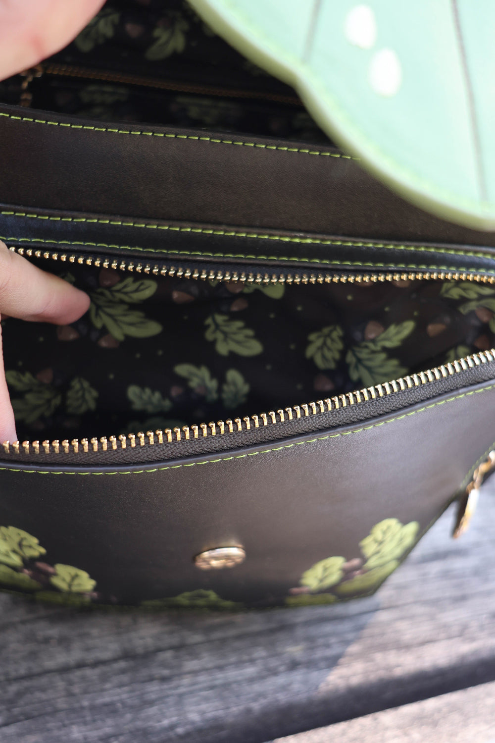 Close-up of the Druid Backpack interior showing oak leaf and acorn patterned lining with a zippered pocket.