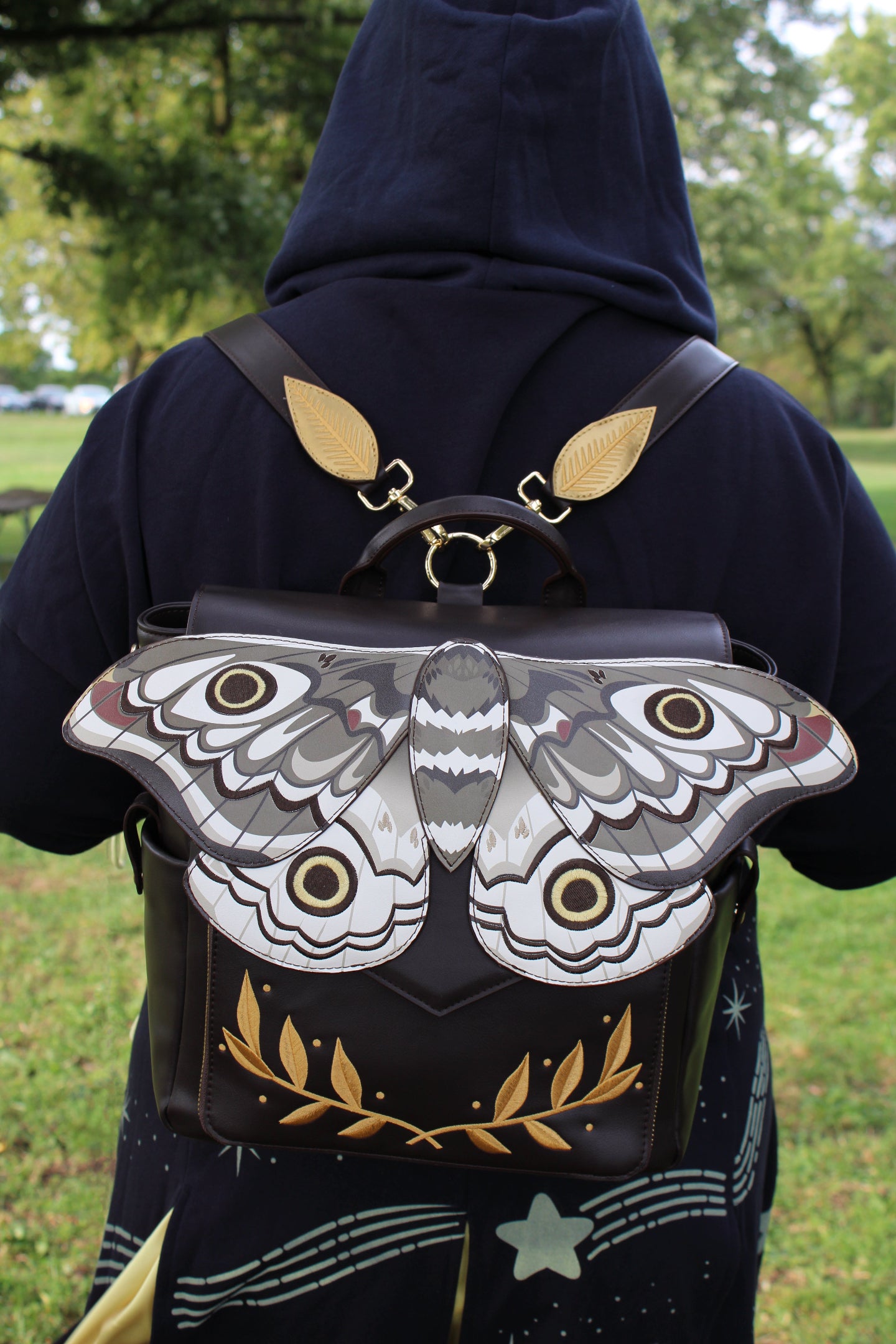 Back view of a model wearing the Emperor Moth Backpack with large emperor moth wing detailing and botanical accents.