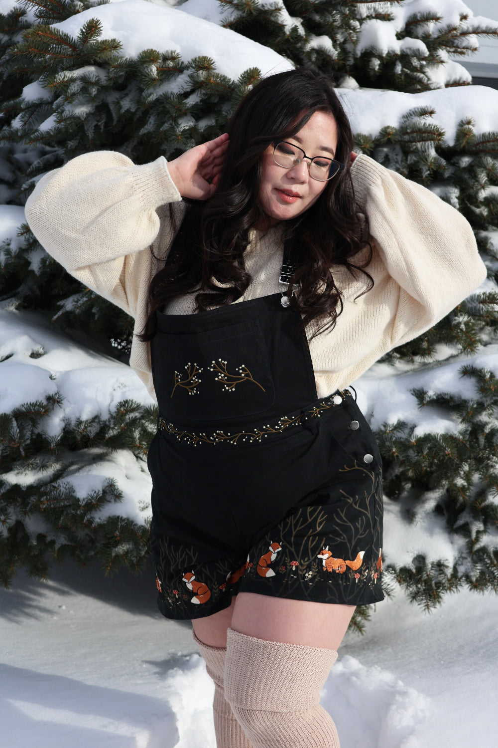 Woman wearing Forest Tale forestcore overalls with fox embroidery in a snowy setting