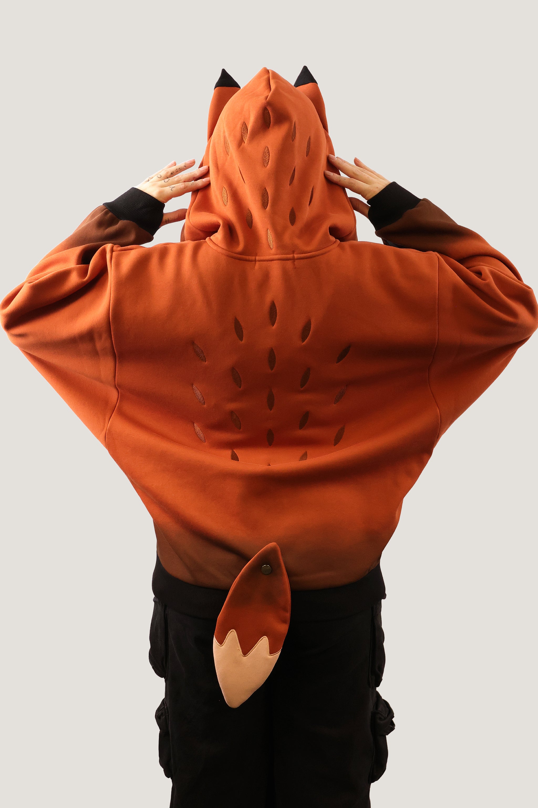 Rear view of the orange Fox Hooded Sweatshirt featuring a detachable plush fox tail and pointed ears on the hood.