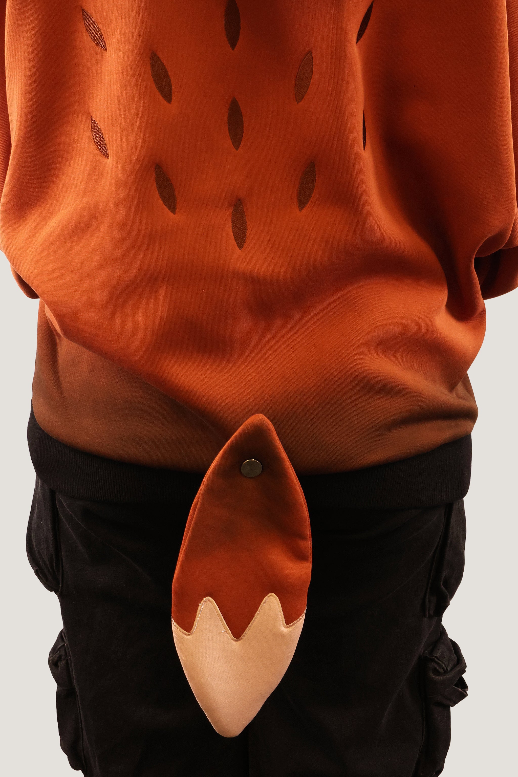 Close-up back view of the Fox Hooded Sweatshirt highlighting the plush orange and cream fox tail and the triangle pattern on the back.