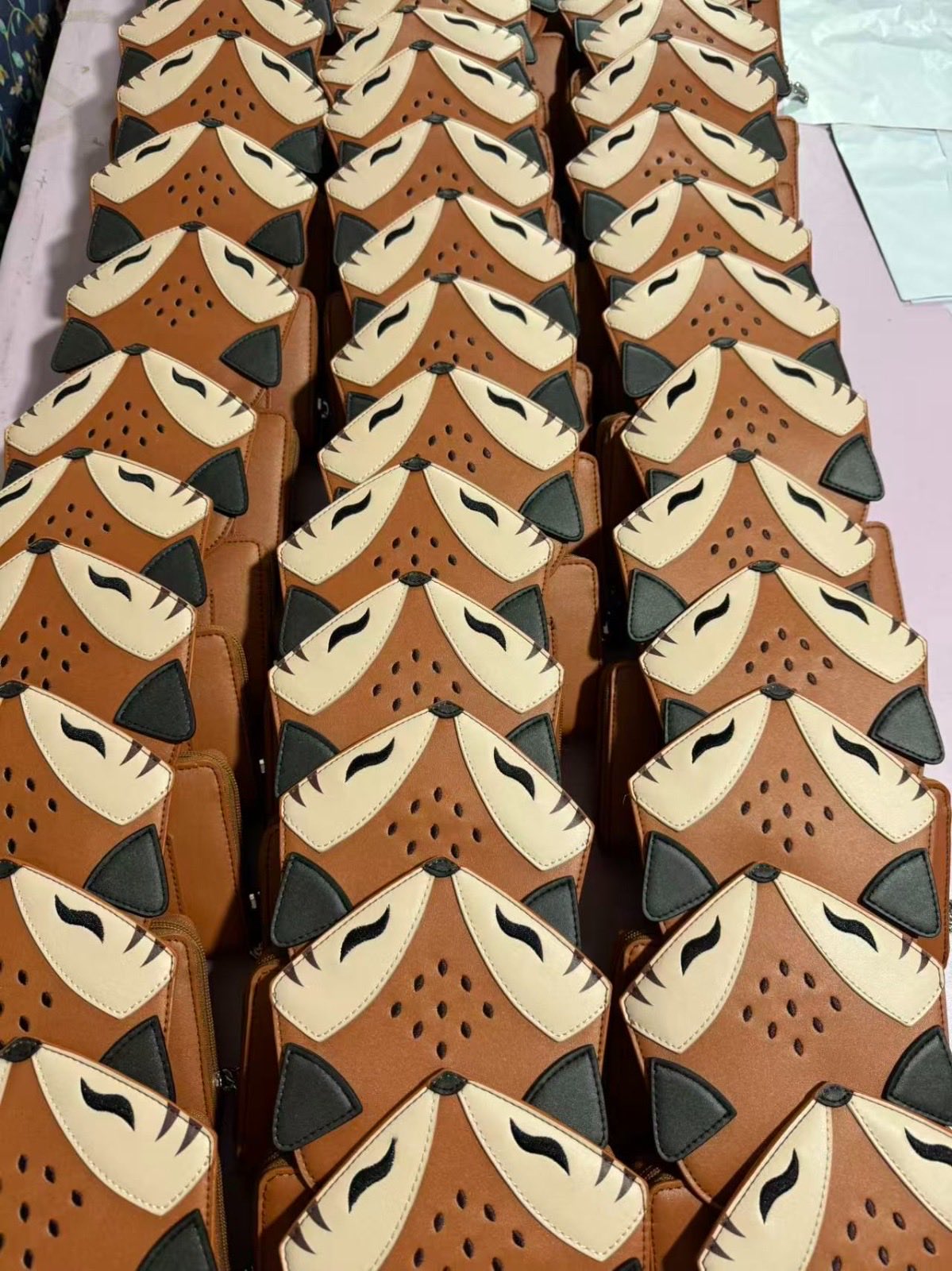 Rows of woodland fox fantasy wallets arranged together during production, featuring fox face details and vegan leather design.