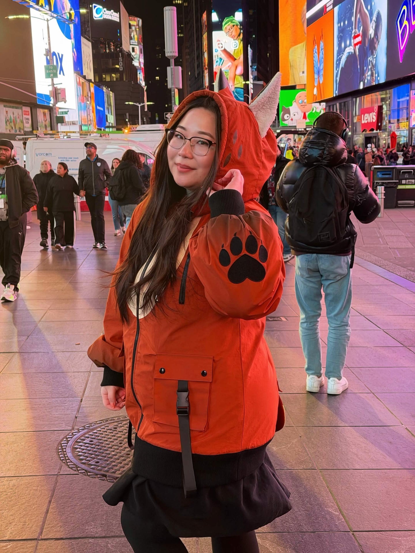 Model wearing a whimsical fox-inspired forestcore jacket with fox ears and paw print details in Times Square at night.