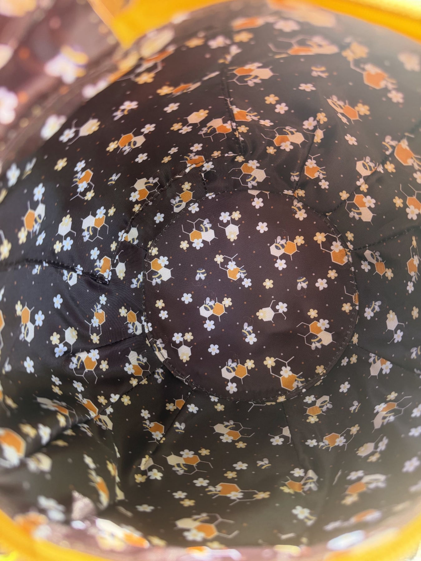 Detailed view inside a honey jar shaped crossbody bag showcasing the custom bee, honeycomb, and floral pattern lining. The spacious interior features a rich brown fabric decorated with tiny bees, white flowers, and honeycomb motifs.