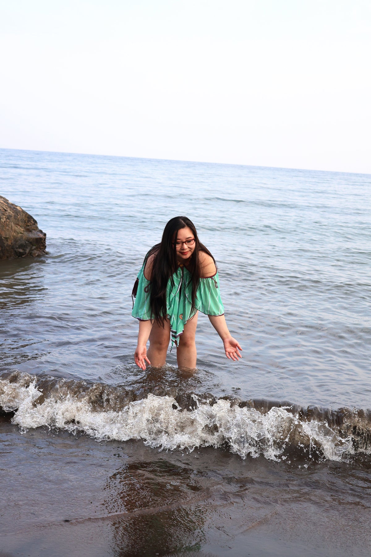 Nyahallo Luna Moth Swimsuit worn in the ocean, featuring a flowing mint green moth wing-inspired cape during a beach photoshoot.