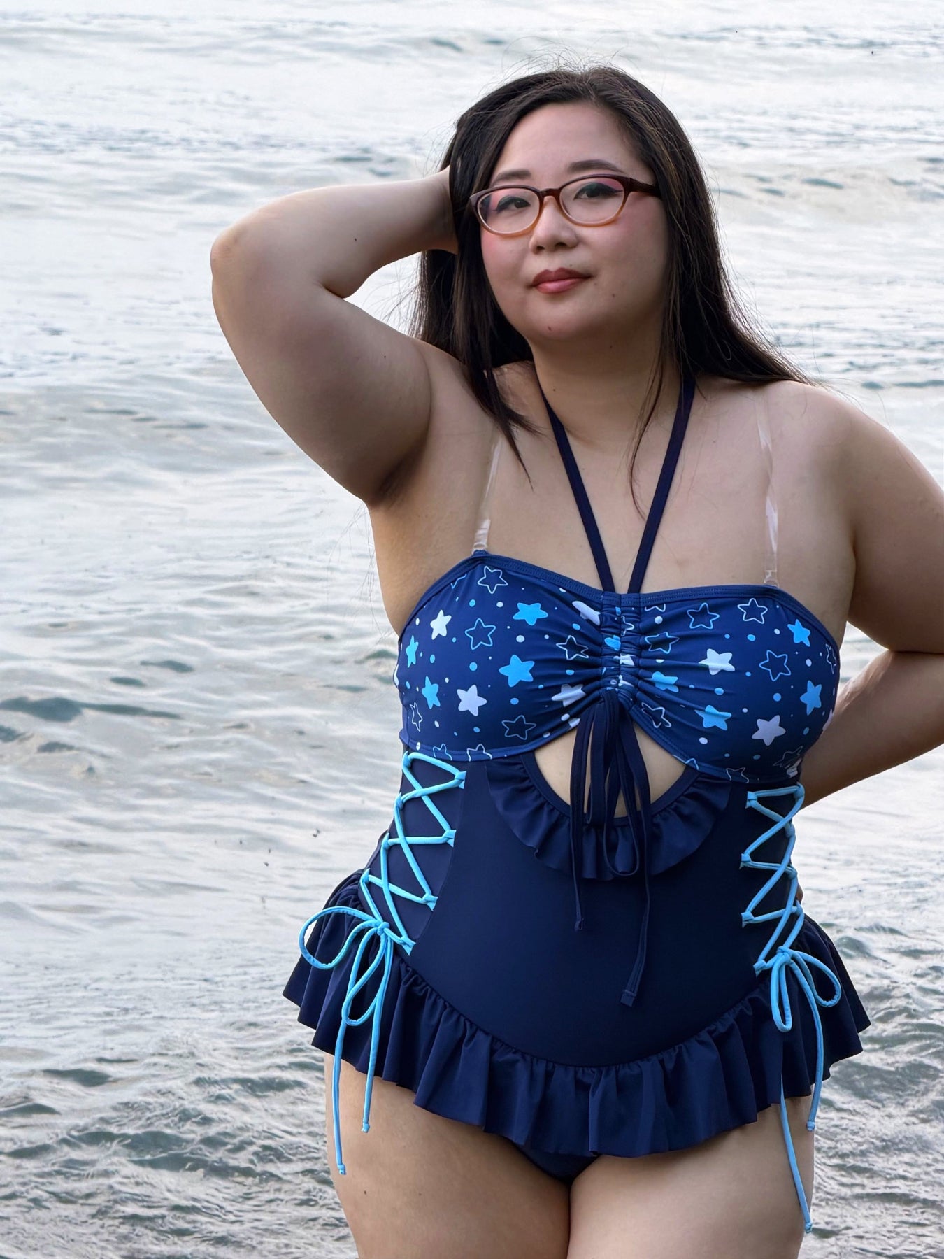 Model wearing Nyahallo's Moon Jellyfish Swimsuit without the cape, featuring a navy star-patterned one-piece with lace-up sides and ruffle details.