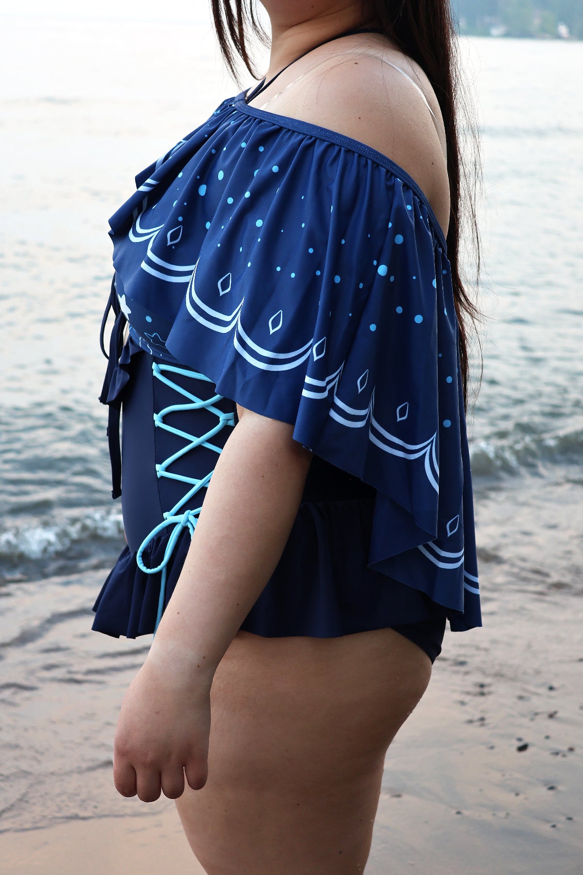Side view of the Nyahallo Moon Jellyfish Swimsuit with the detachable moon jellyfish-inspired cape, showcasing the flowing layered cape, side lace-up detail, and ocean-inspired print.