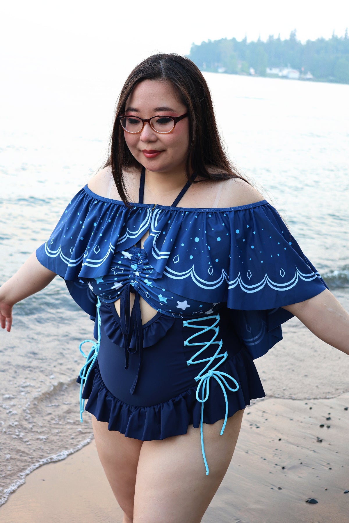 Model wearing the Nyahallo Moon Jellyfish Swimsuit with the detachable jellyfish-inspired cape, featuring a star-patterned bust, lace-up sides, and flowing ocean-inspired cape.