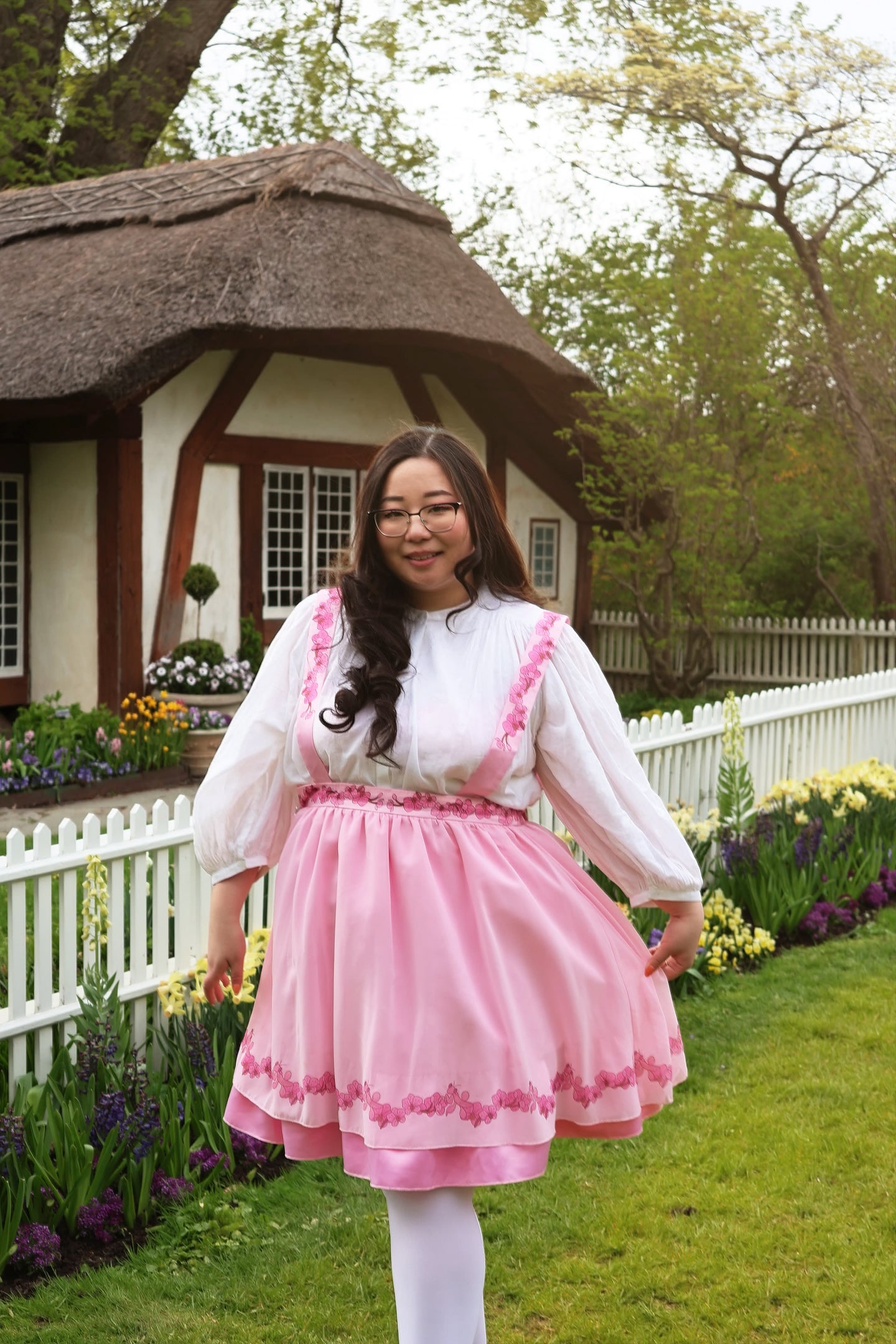 Pink Orchid Pinafore Skirt with floral lace trim and cottagecore fairycore styling photographed in a botanical garden.