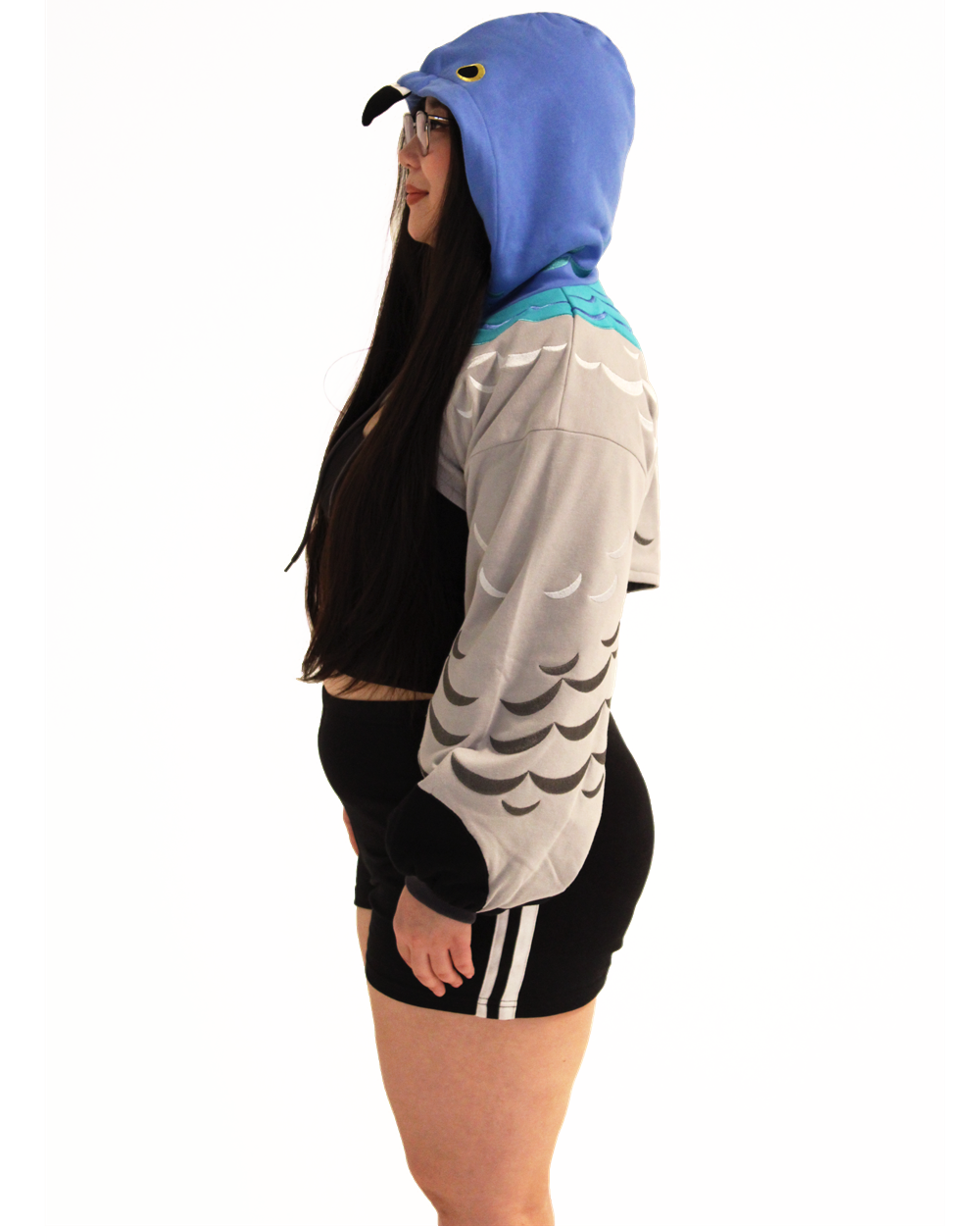 Side profile of a model wearing a pigeon themed cropped shrug with feather patterned sleeves and bird hood.