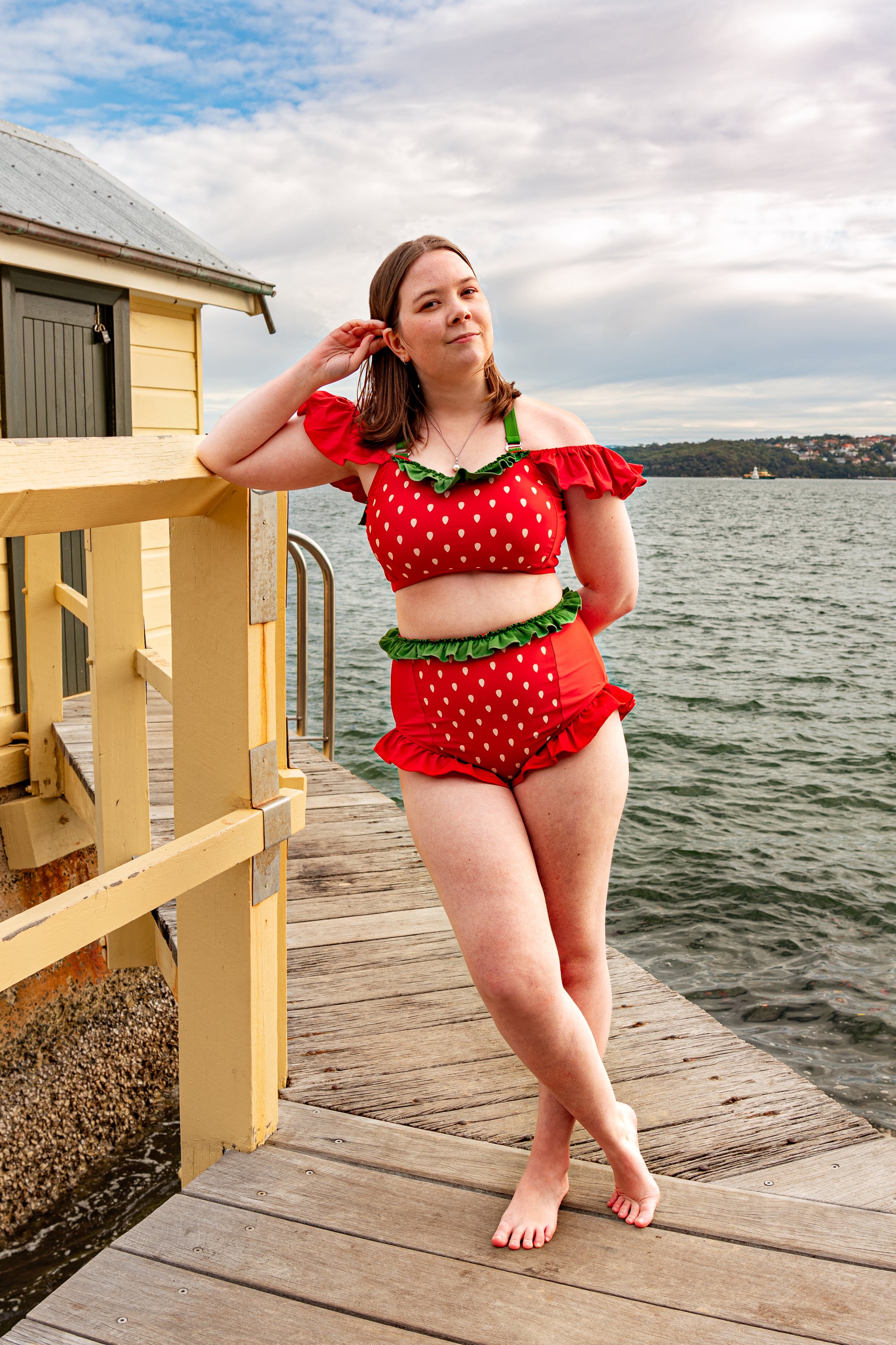 Cute strawberry themed bikini set with frilly red ruffles and green trim styled at the beach.