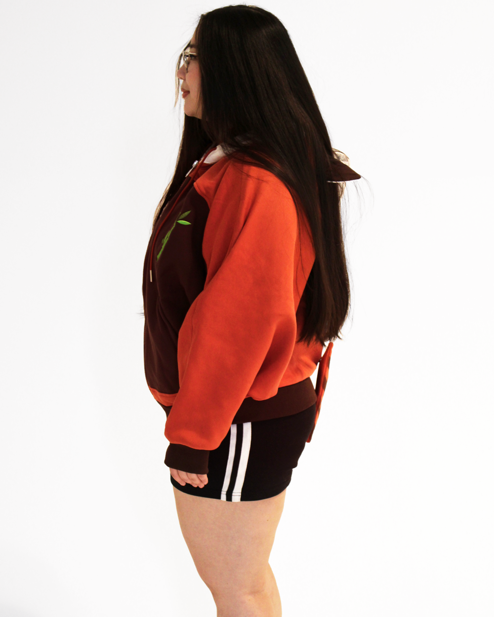 Side view of a model wearing a red panda themed oversized hoodie with orange sleeves and bamboo embroidery.