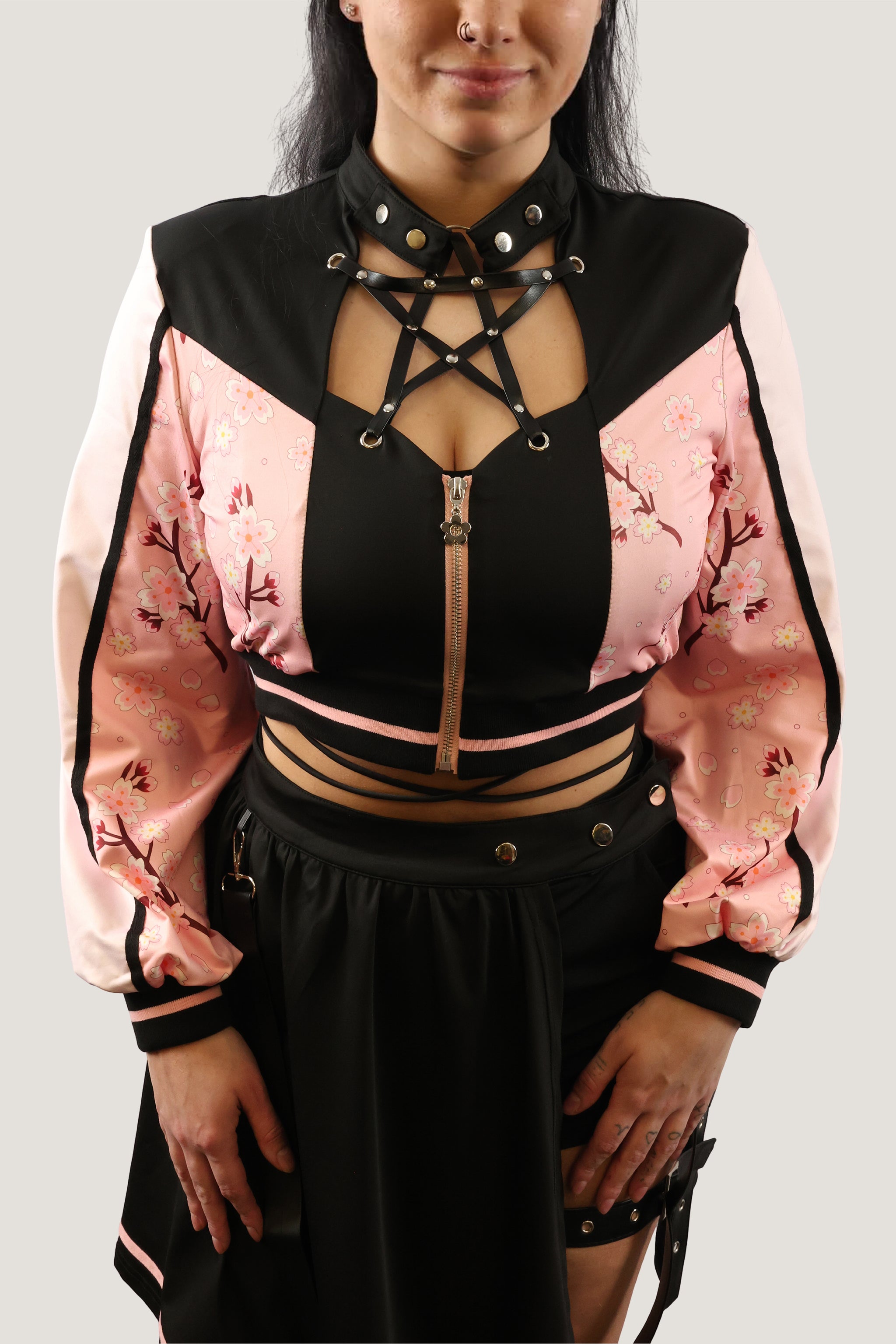 Model wearing a black and pink outfit with intricate designs on a plain background