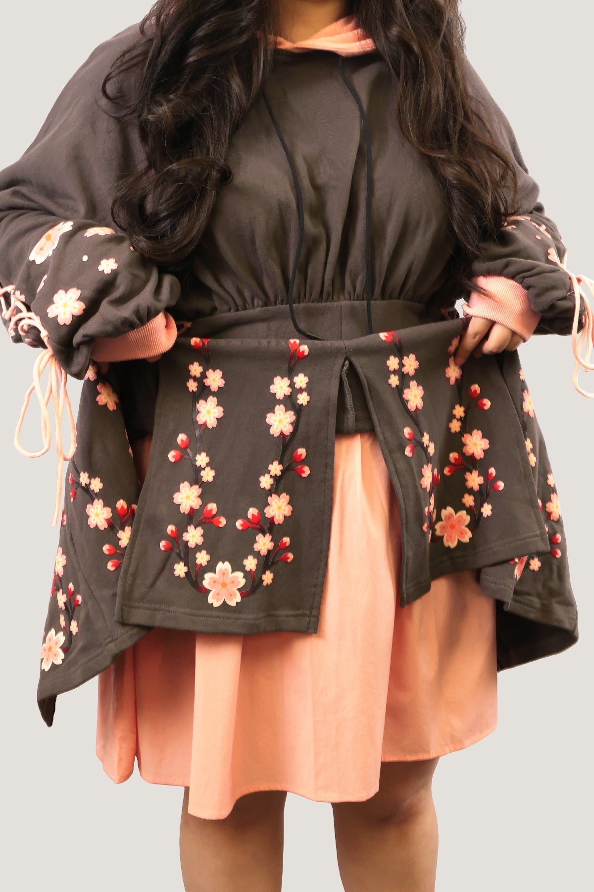 Layered skirt detail of the Sakura Hoodie Dress featuring cherry blossom panels over a pink underskirt.