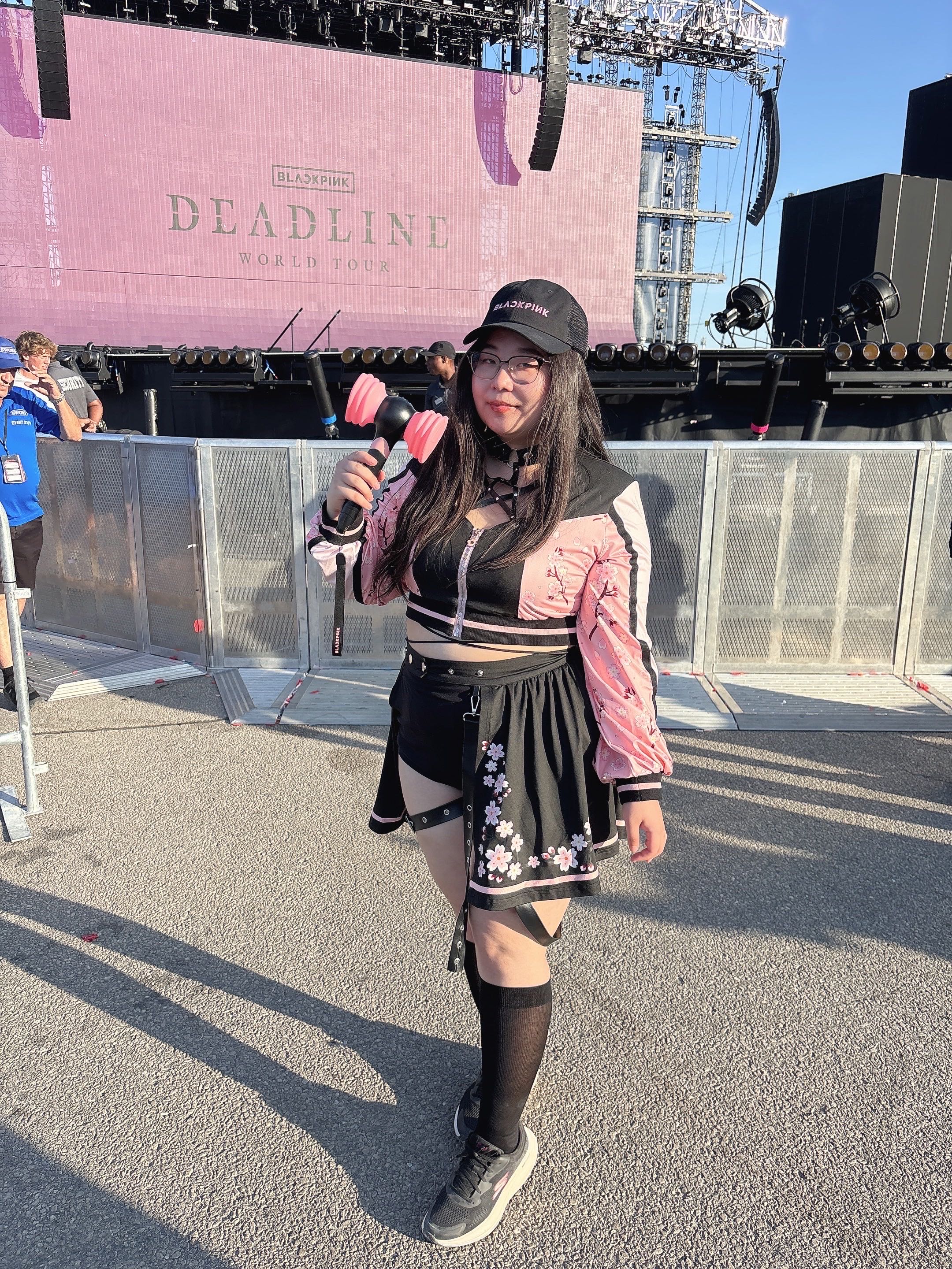 Close-up lifestyle photo of the Sakura superstar set being worn at a BLACKPINK concert, showing the pink floral sleeves and cherry blossom skirt details.