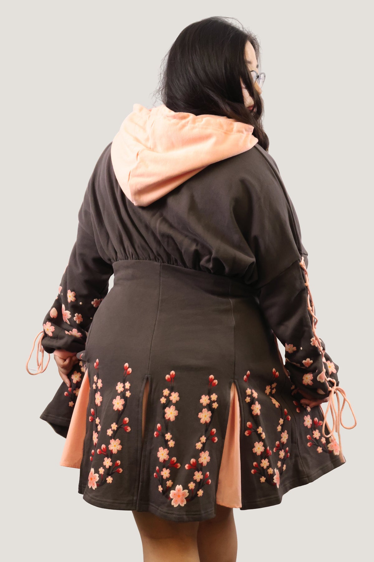 Back view of the Sakura Hoodie Dress with the hood down, featuring cherry blossom details and a pink hood lining.