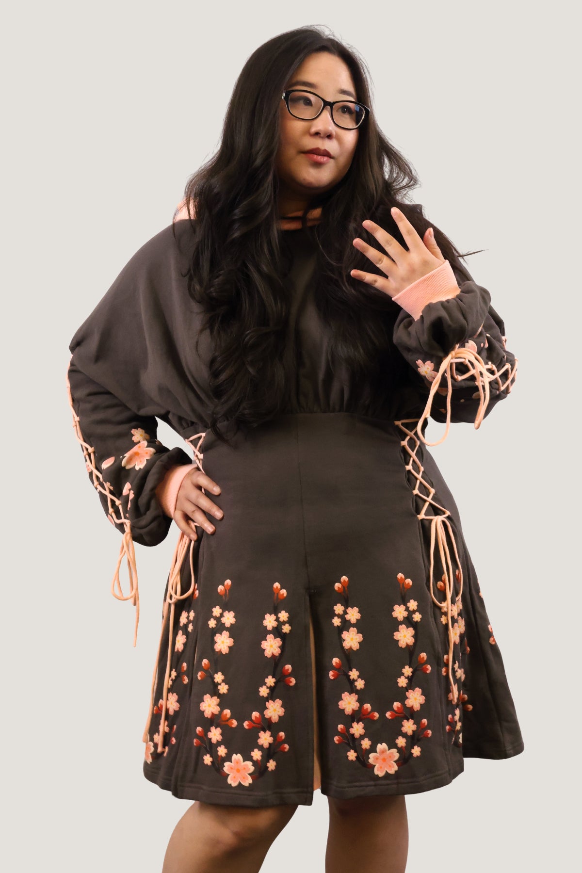 Angled front view of the Sakura Hoodie Dress featuring lace-up sleeves, lace-up sides, and cherry blossom details.
