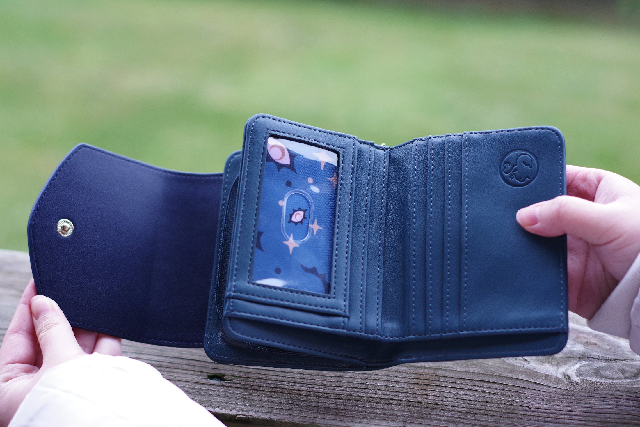 Open Seraphim celestial wallet showing blue interior lining, multiple card slots, clear ID window, and zip compartment.
