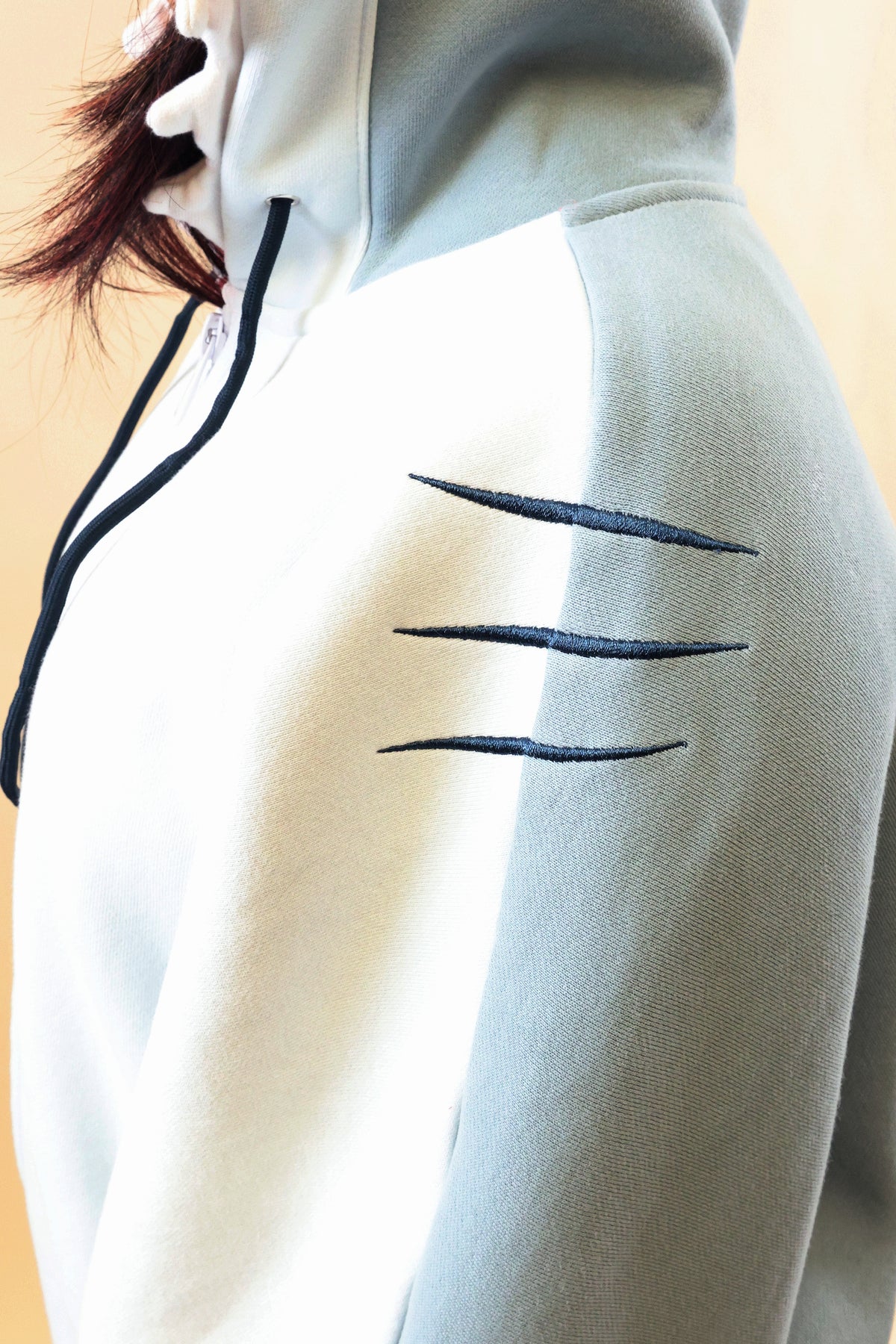 Close-up of the Nyahallo Shark Hoodie, highlighting its light blue and white fabric, dark blue embroidered gill details on the shoulder, and soft material texture.