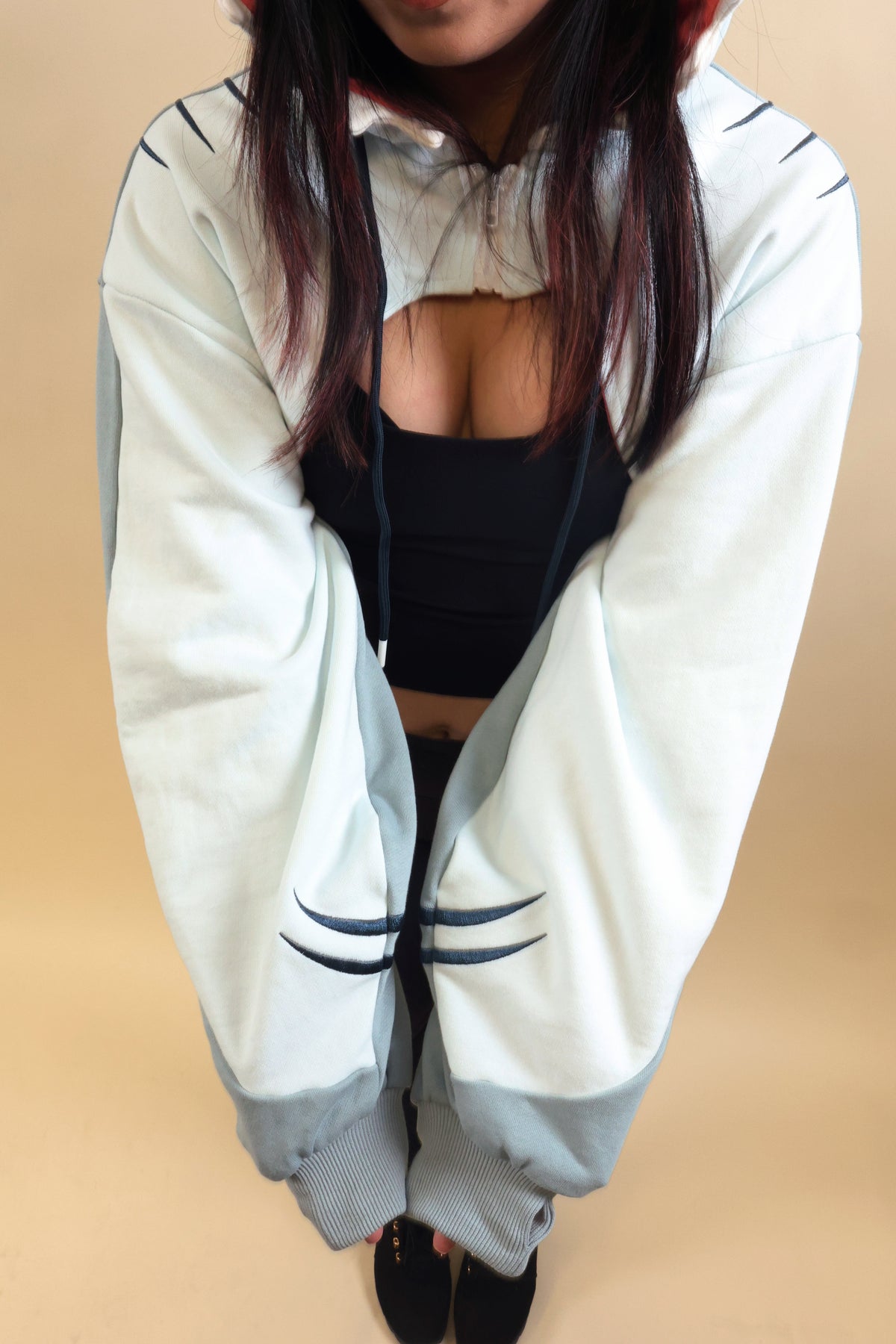 Close-up of the Nyahallo Shark Shrug, highlighting its oversized light blue and white sleeves, embroidered shark gill details, ribbed cuffs, and cropped zip-up design.