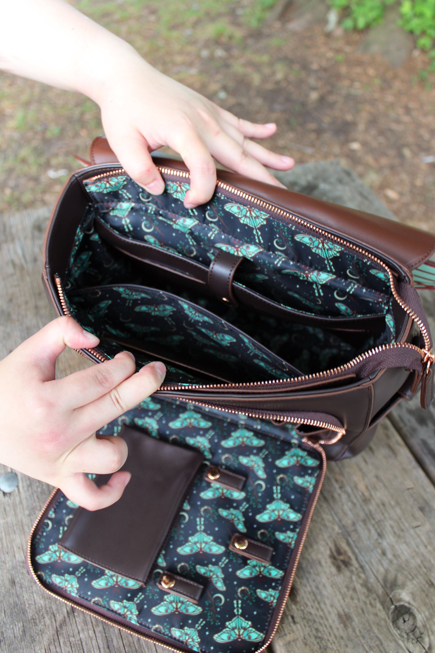 Open view of Nyahallo's Spanish Moon Moth Backpack showing interior lining, compartments, and printed moth pattern fabric