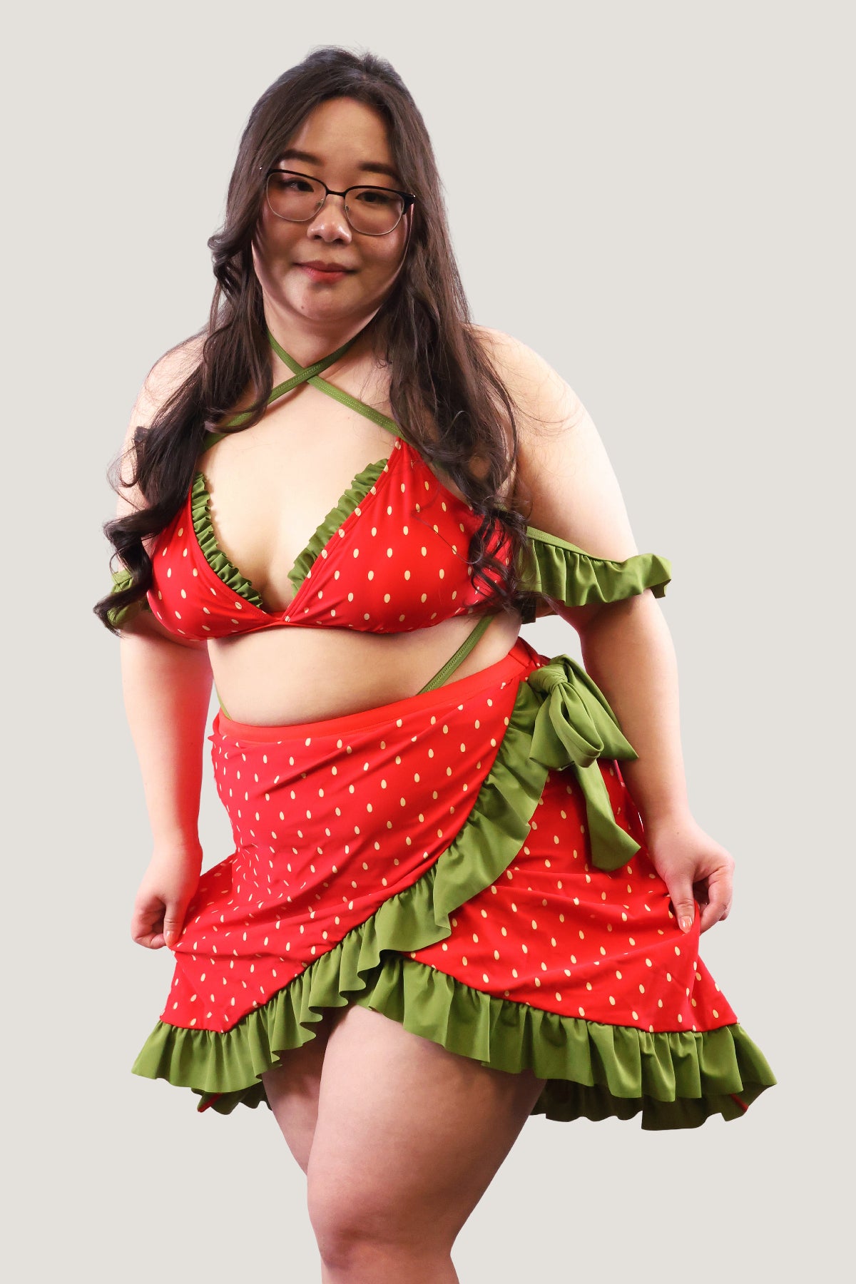 Model wearing a red and green outfit with ruffled details on a plain background