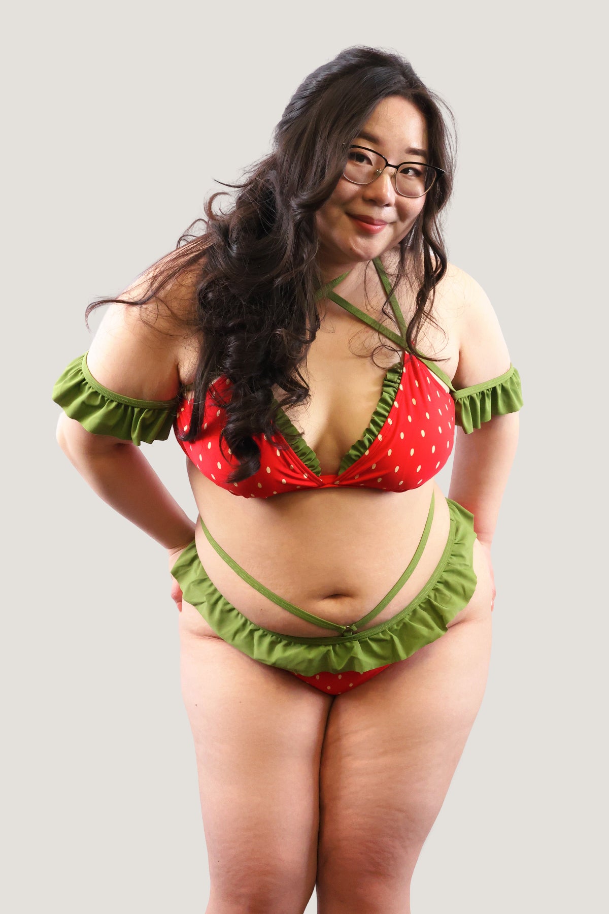 Model wearing a red and green strawberry-themed bikini against a plain background