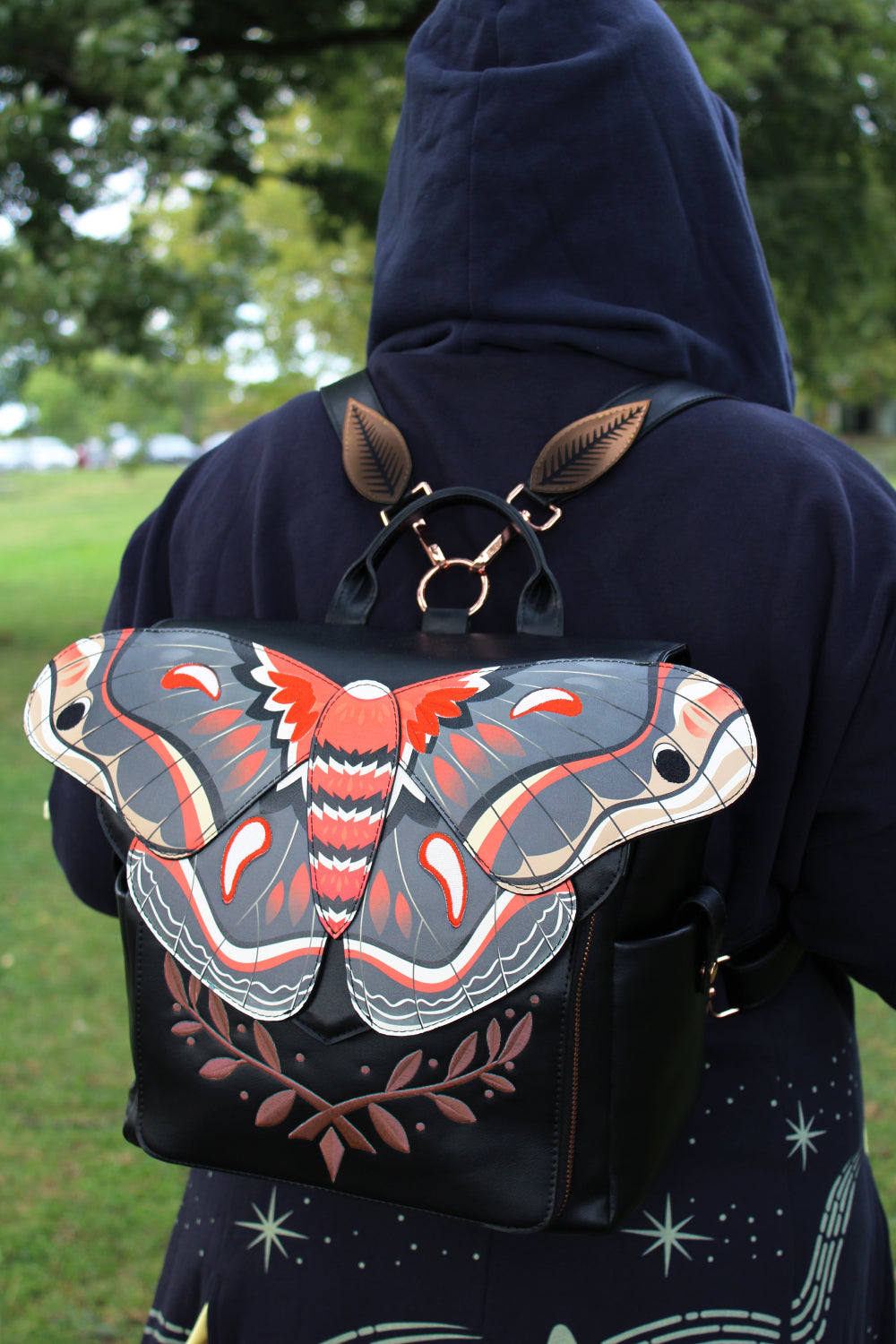 Black wearable art backpack featuring a large cecropia moth design with botanical woodland details designed in a fairycore style.