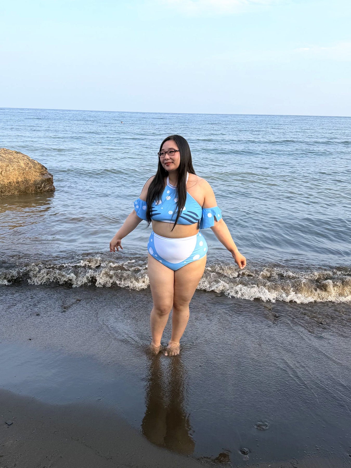 Model wearing the blue and white Whale Shark two-piece swimsuit while standing in shallow ocean water at the beach.