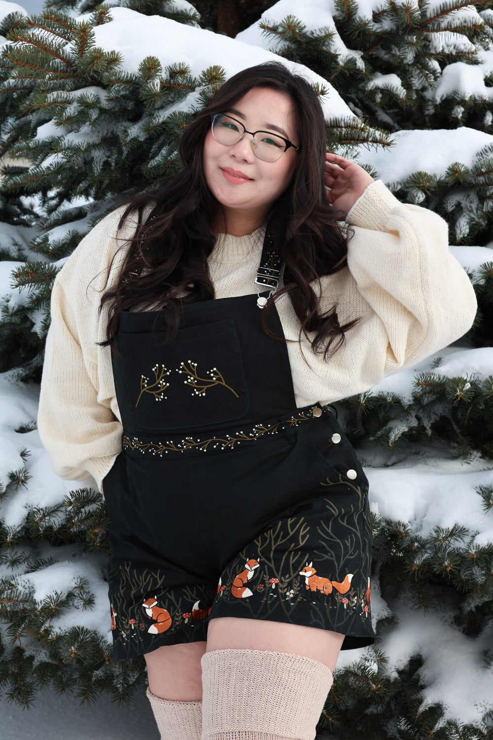 Whimsical forestcore fox overalls styled with a cozy cream sweater in a snowy winter setting.
