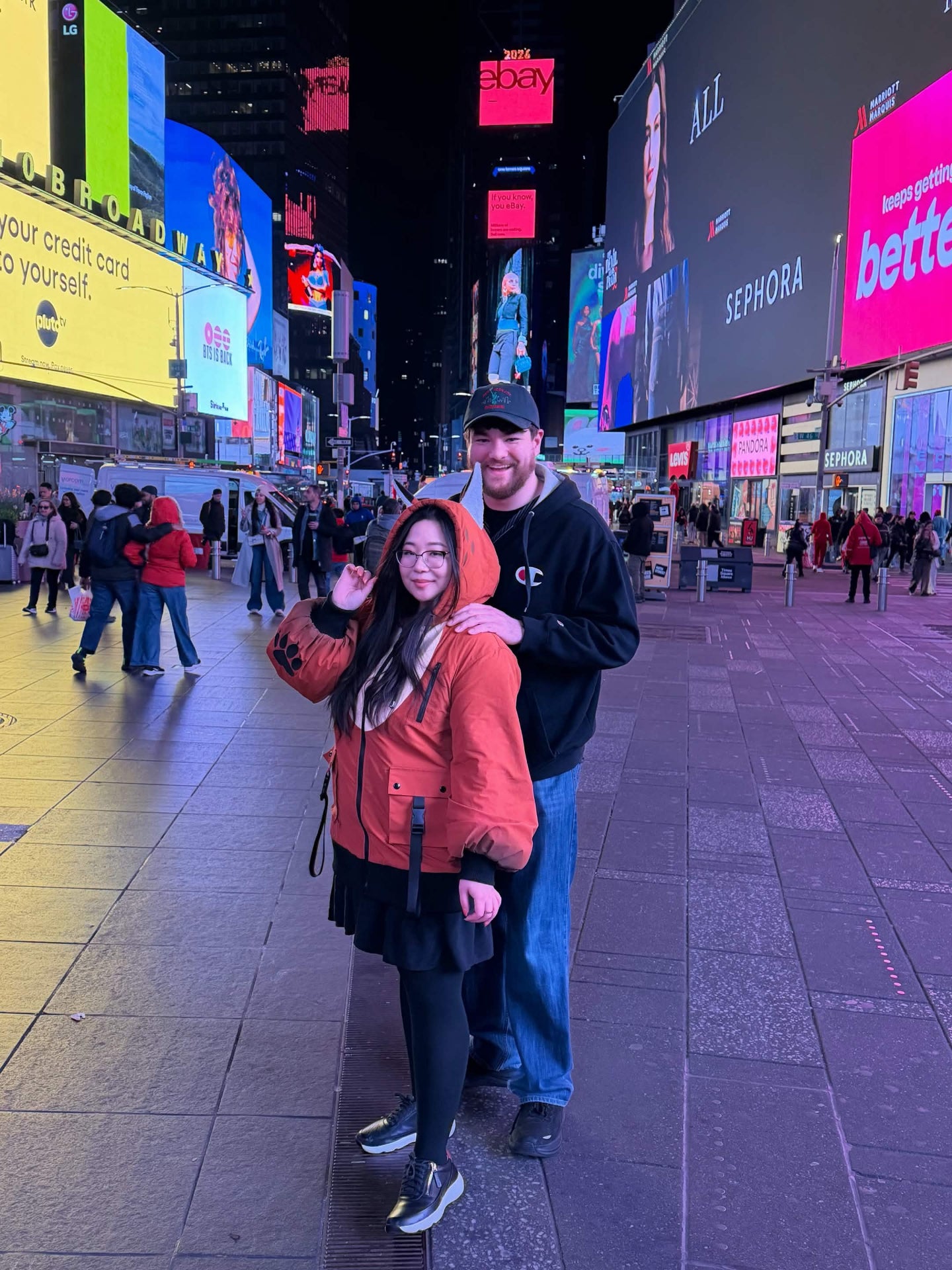 Person wearing a whimsical fox-inspired jacket with animal ears in Times Square at night.