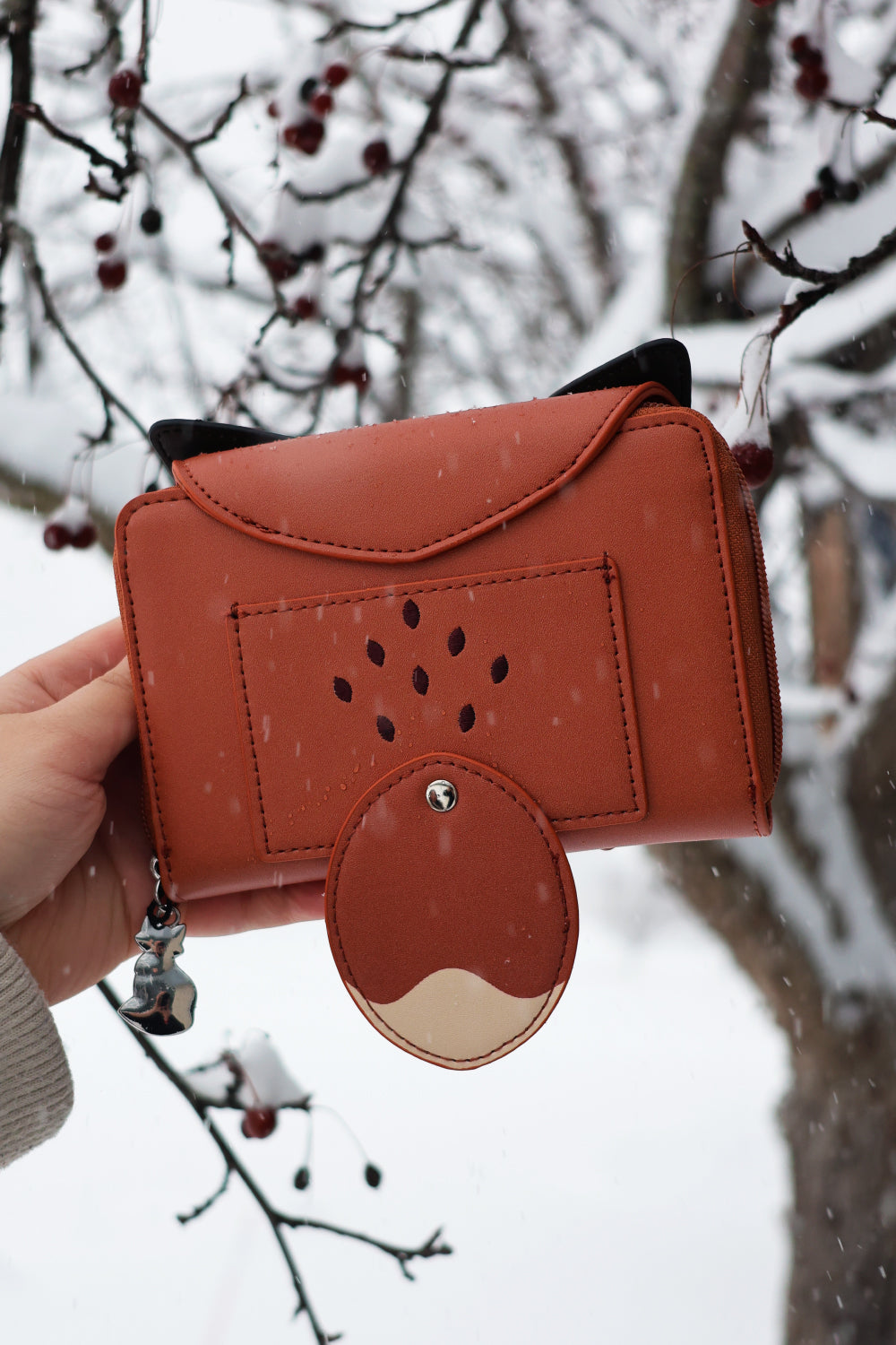 Back view of a woodland fox fantasy wallet with tail detail and vegan leather design held outdoors in falling snow.