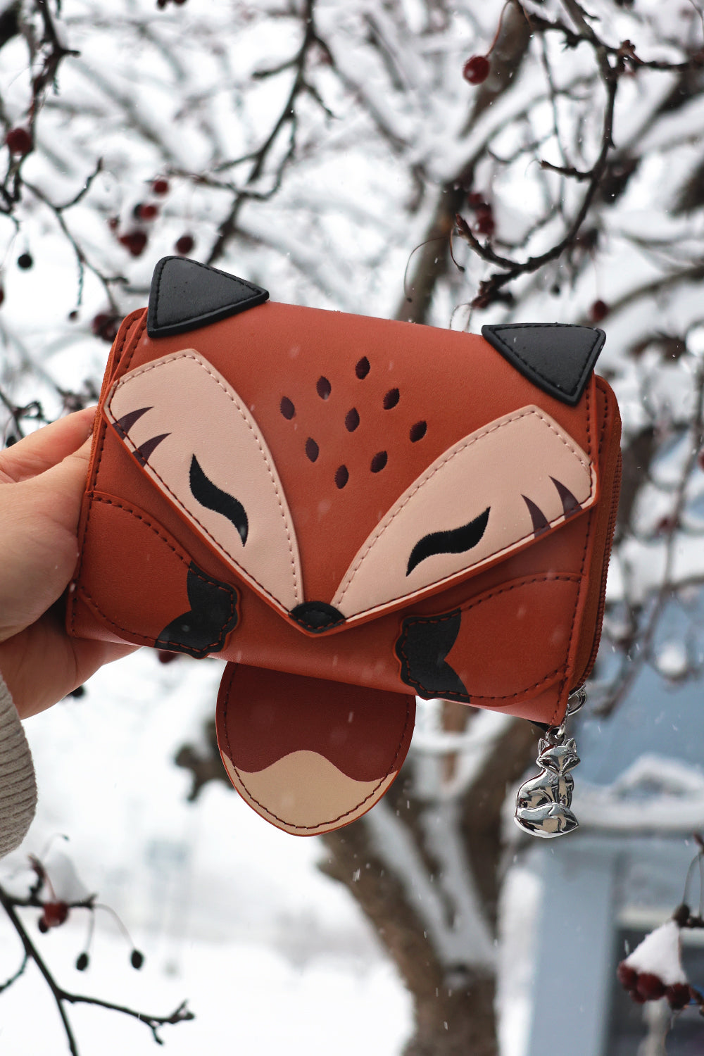 Woodland fox fantasy wallet with tail detail and silver fox charm held outdoors in snowy winter scenery.