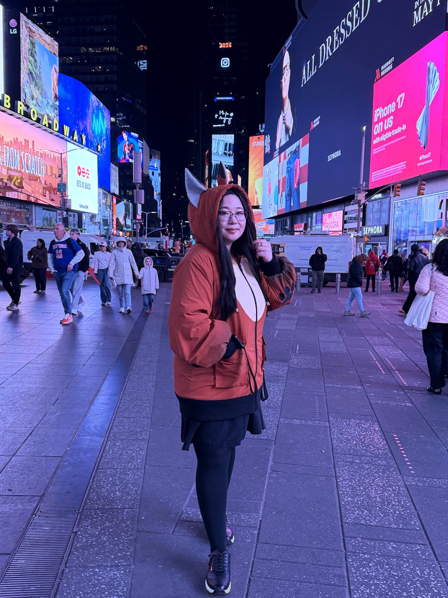 Model wearing a woodland-inspired fox ear jacket in Times Square at night with illuminated billboards.