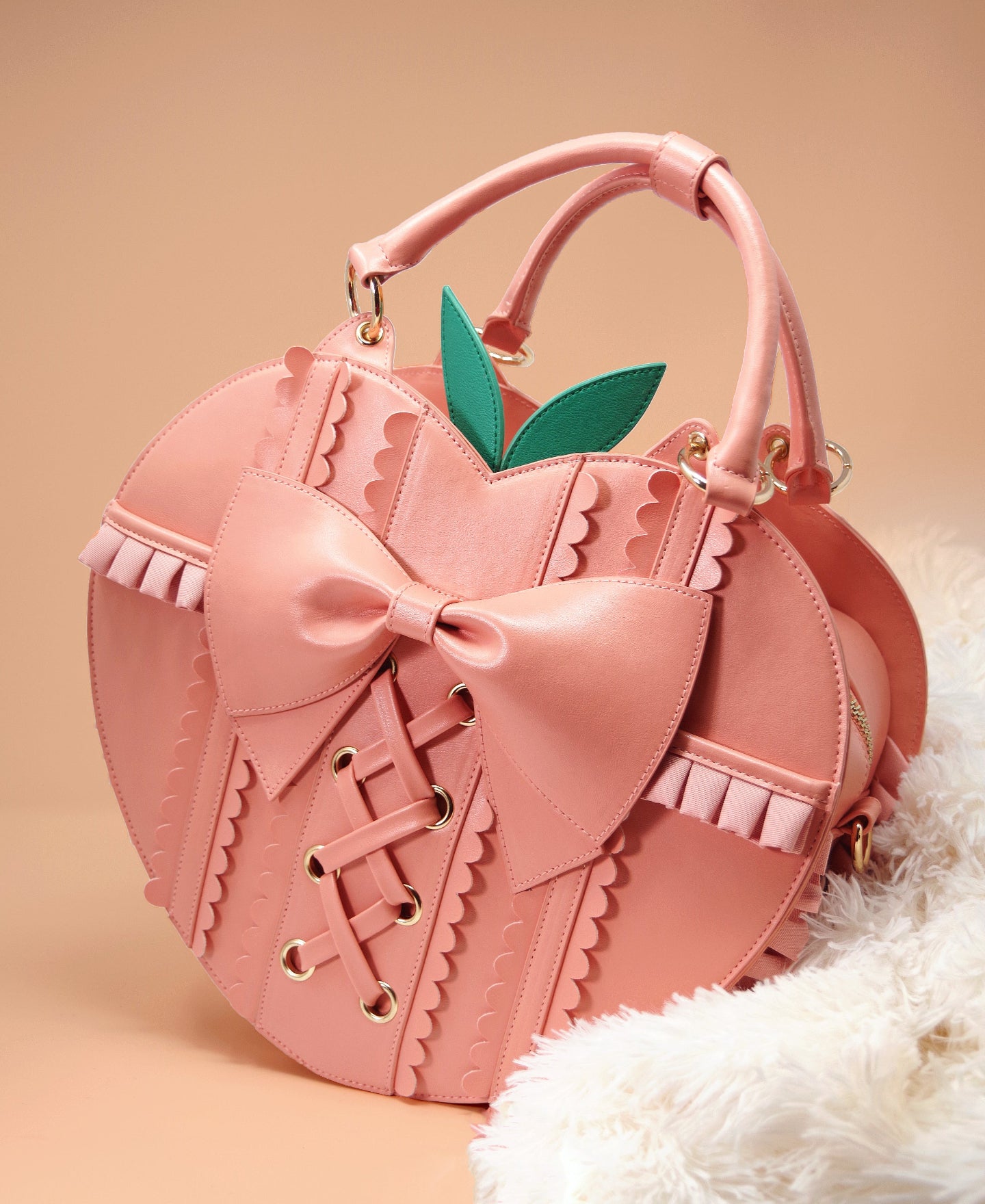 Peach-shaped purse with lace-up embroidery, oversized bow, removable leaf accents, ruffled trim, and top handles from the Frilly Fruits collection.