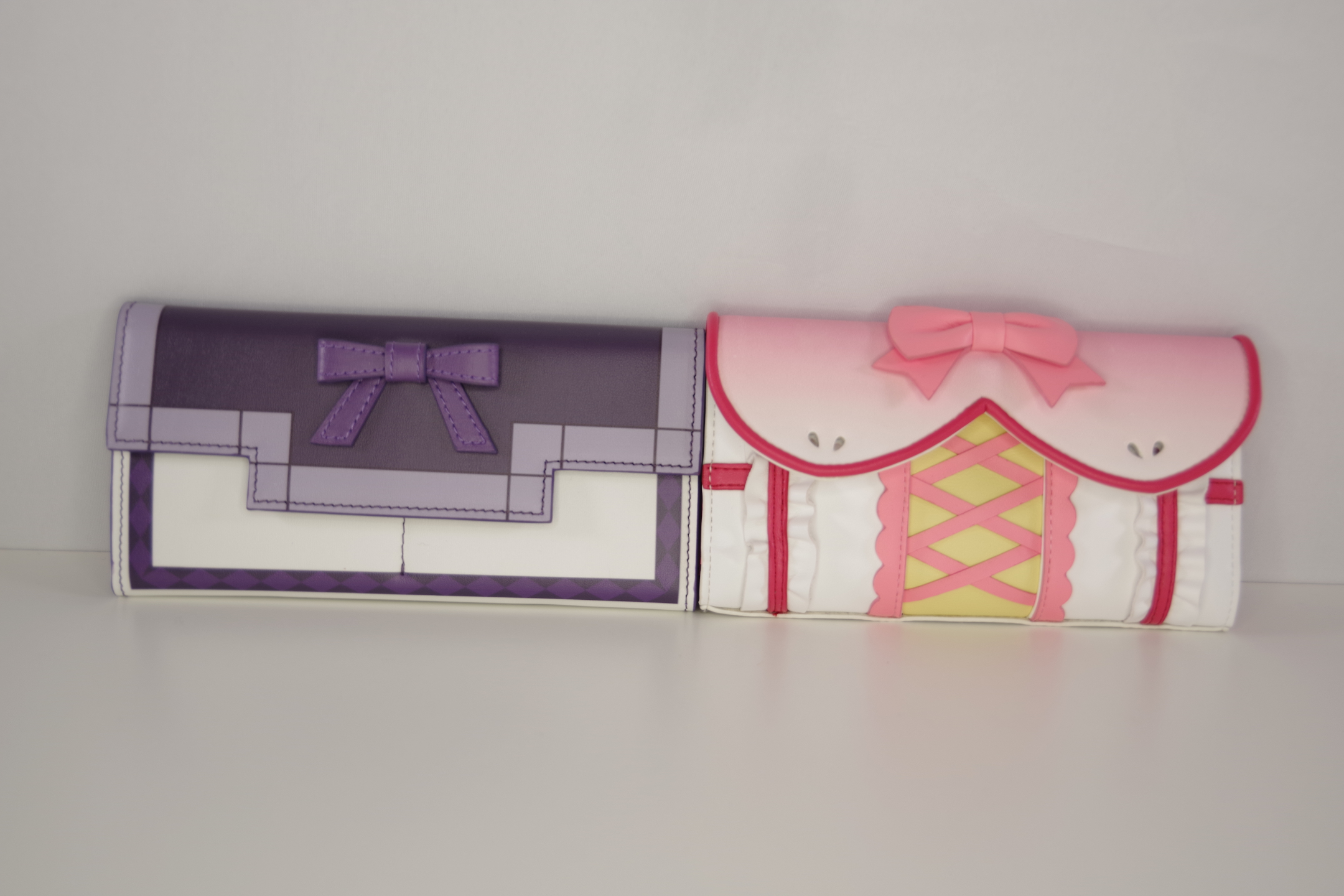 Pink Madoka inspired wallet and purple Homura inspired wallet displayed side by side for size and design comparison.