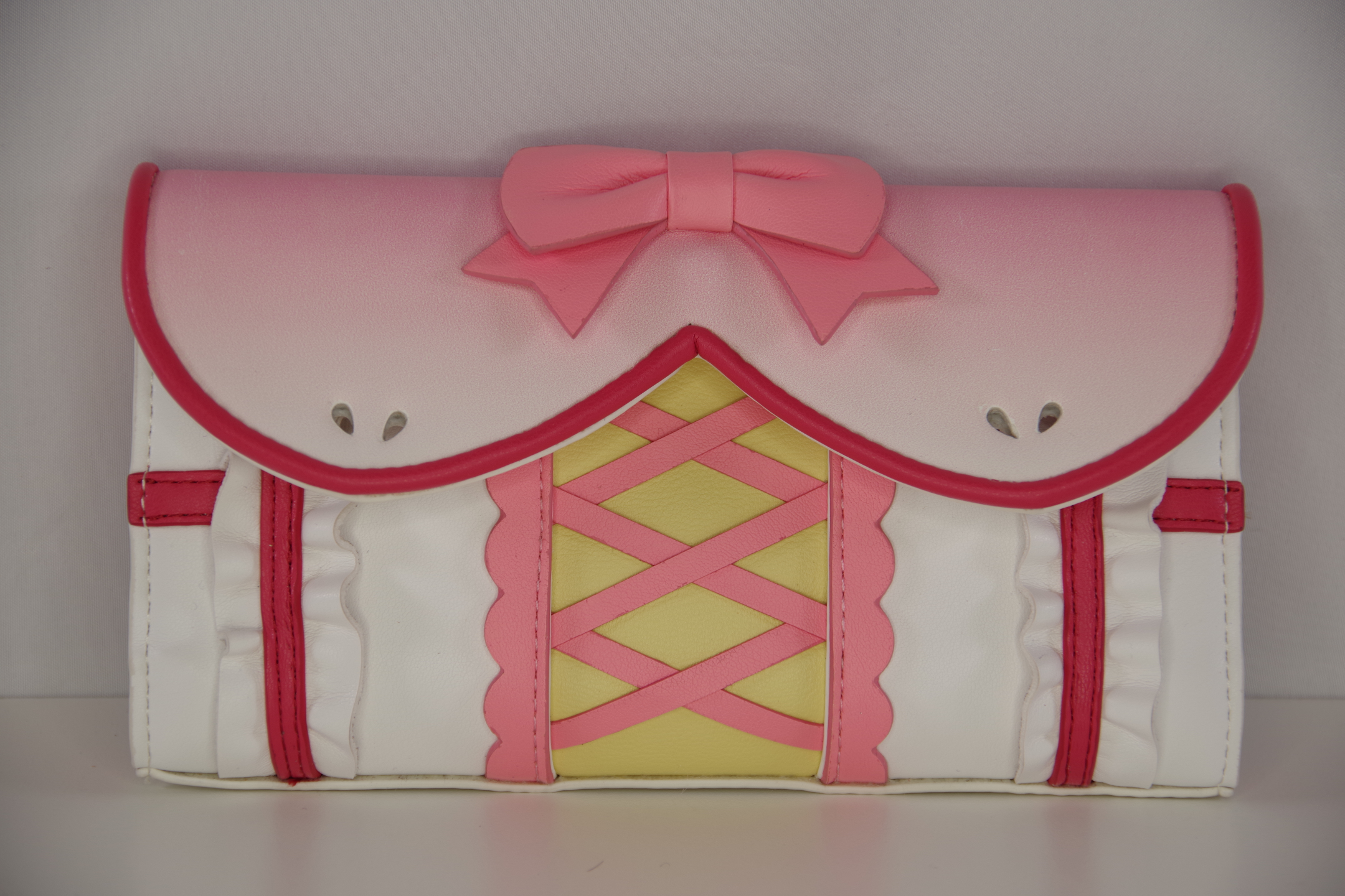 Front view of a pink magical girl wallet featuring a bow accent, corset-inspired lacing, ruffle details, and kawaii anime fashion styling.