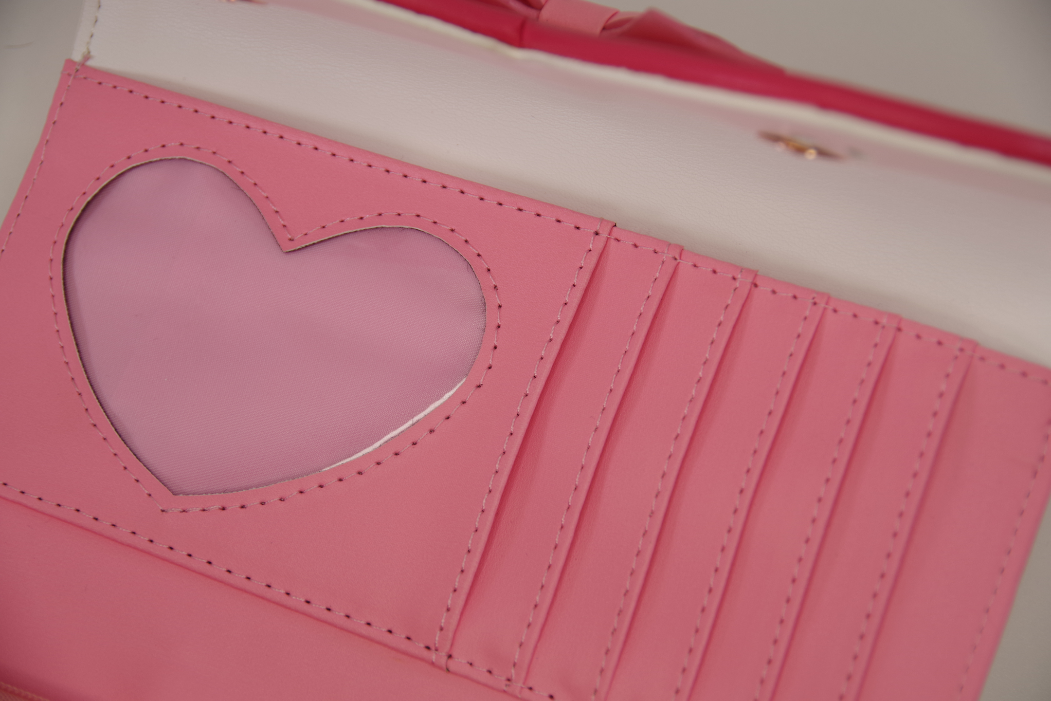 Interior of a pink magical girl inspired wallet featuring a heart-shaped ID window, multiple card slots, and a zippered coin compartment.
